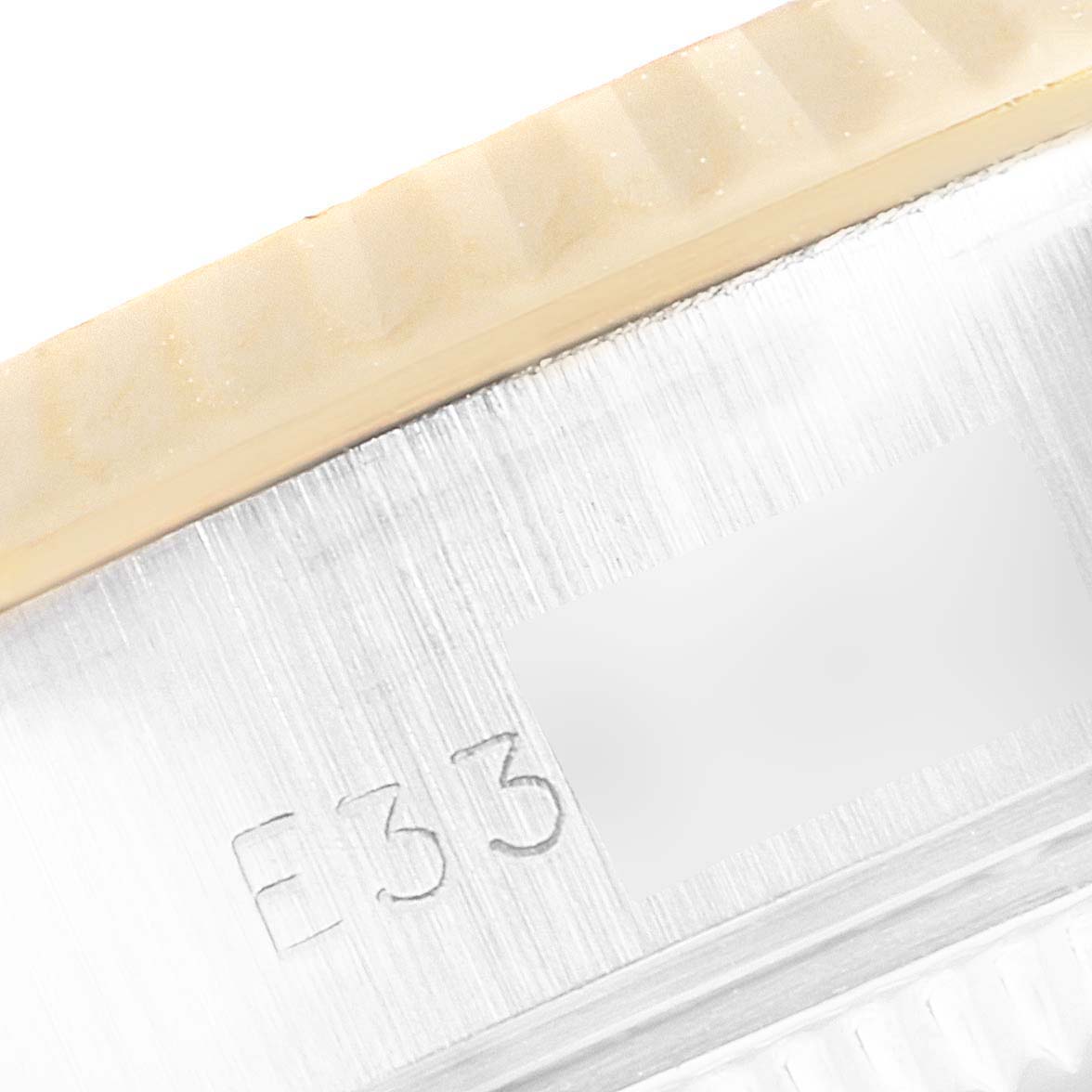 This close-up image of the Rolex Datejust 69173 Women's Steel and Gold (two tone) Champagne Dial 69173 Women's Steel and Gold (two tone) Champagne Dial watch shows part of the fluted bezel and a section of the inner case with the engraving.