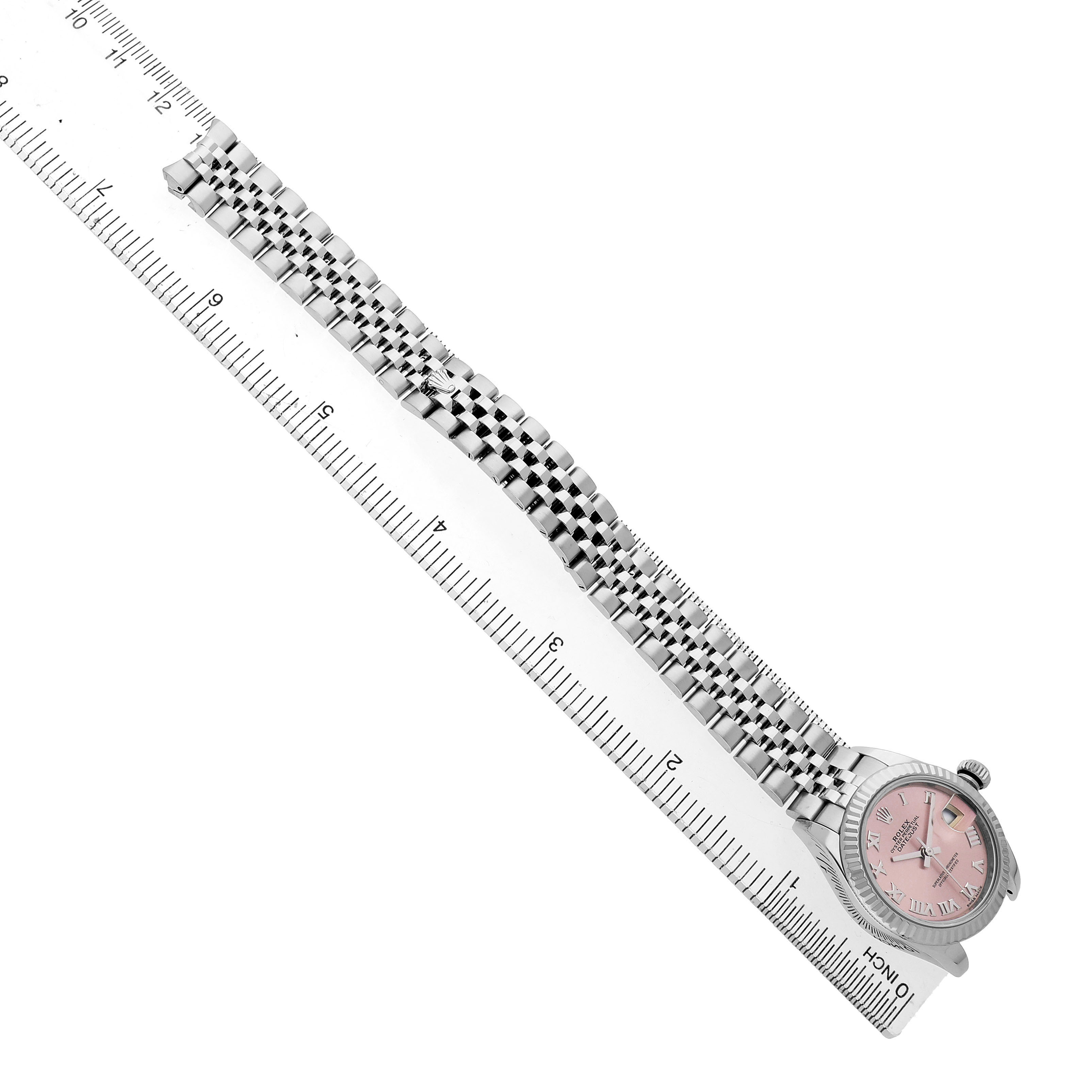 The Rolex Datejust 279174 Women's Stainless Steel Pink Dial watch is photographed from an angled top-down view, showing the bracelet and case alongside a ruler.