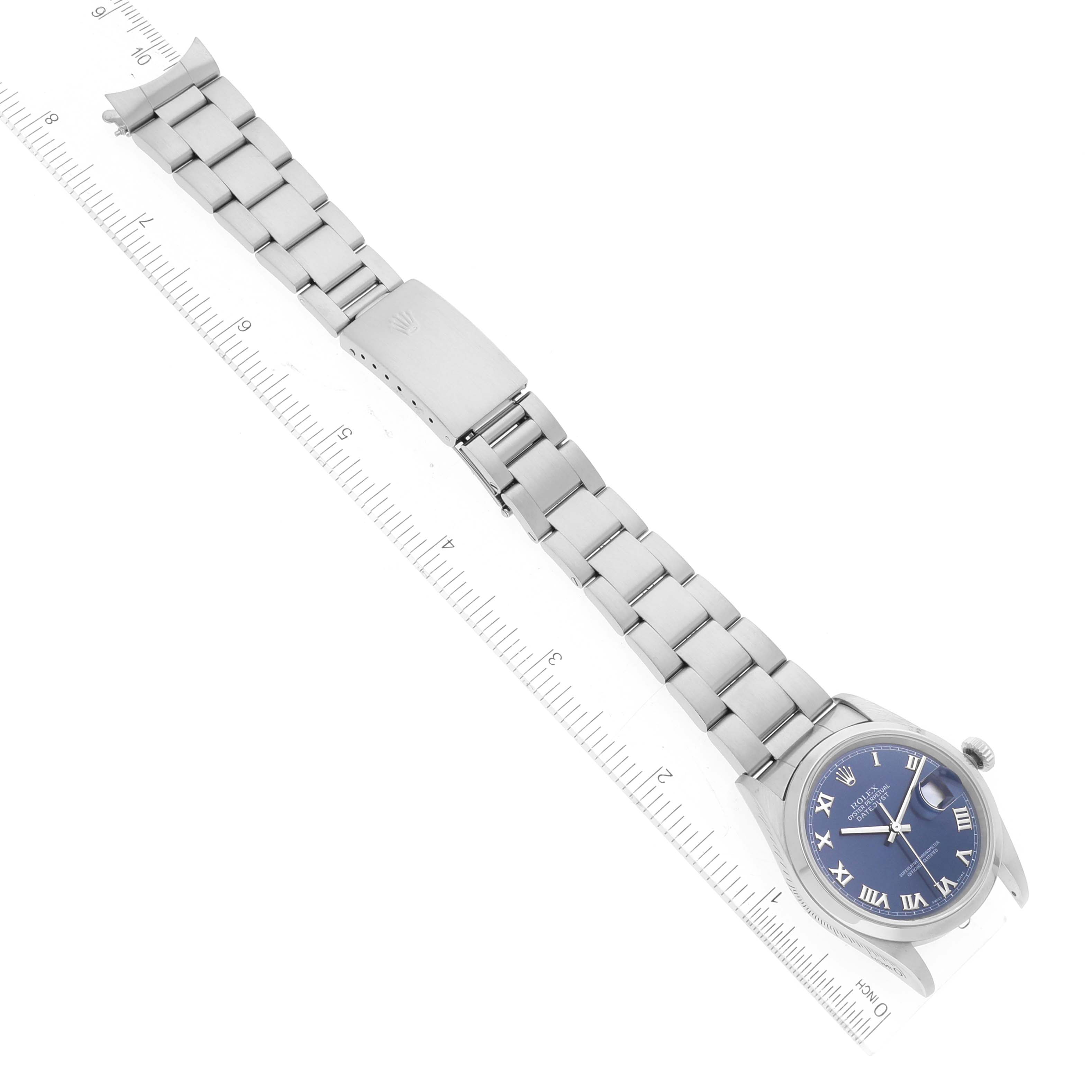 The image shows a top-down view of a Rolex Datejust 16200 Men's Stainless Steel Blue Dial 16200 Men's Stainless Steel Blue Dial watch, displaying its bracelet, clasp, and blue Roman numeral dial alongside a ruler for scale.