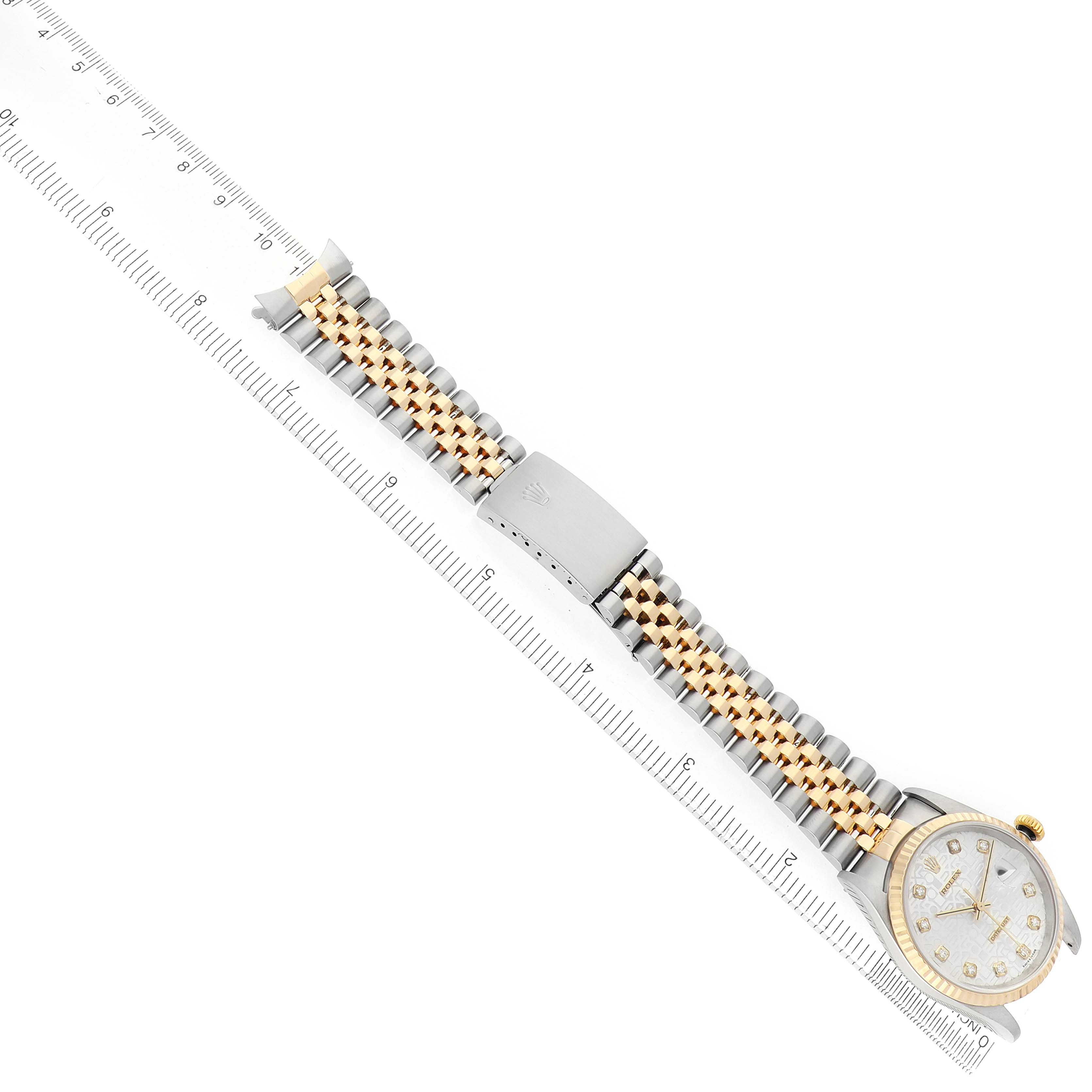 The Rolex Datejust 16233 Men
s Steel and Gold (two tone) Silver Dial watch is shown at an angled top view, highlighting the gold and silver bracelet and face alongside a ruler.