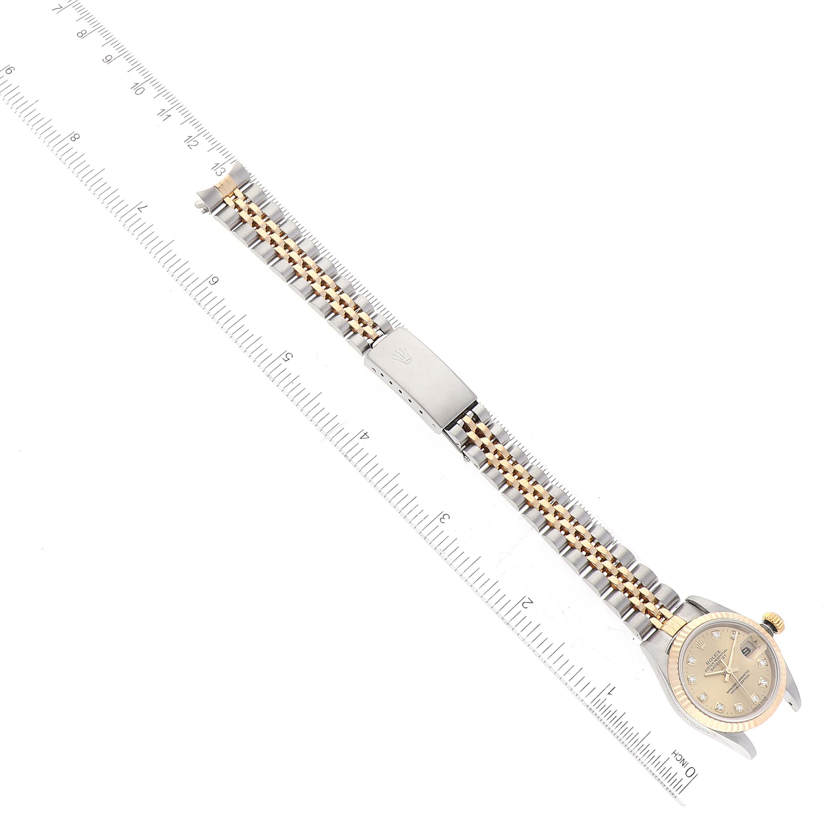 This image shows a top view of a Rolex Datejust 79173 Women's Steel and Gold (two tone) Champagne Dial 79173 Women's Steel and Gold (two tone) Champagne Dial watch with a ruler placed alongside its bicolored metal bracelet.