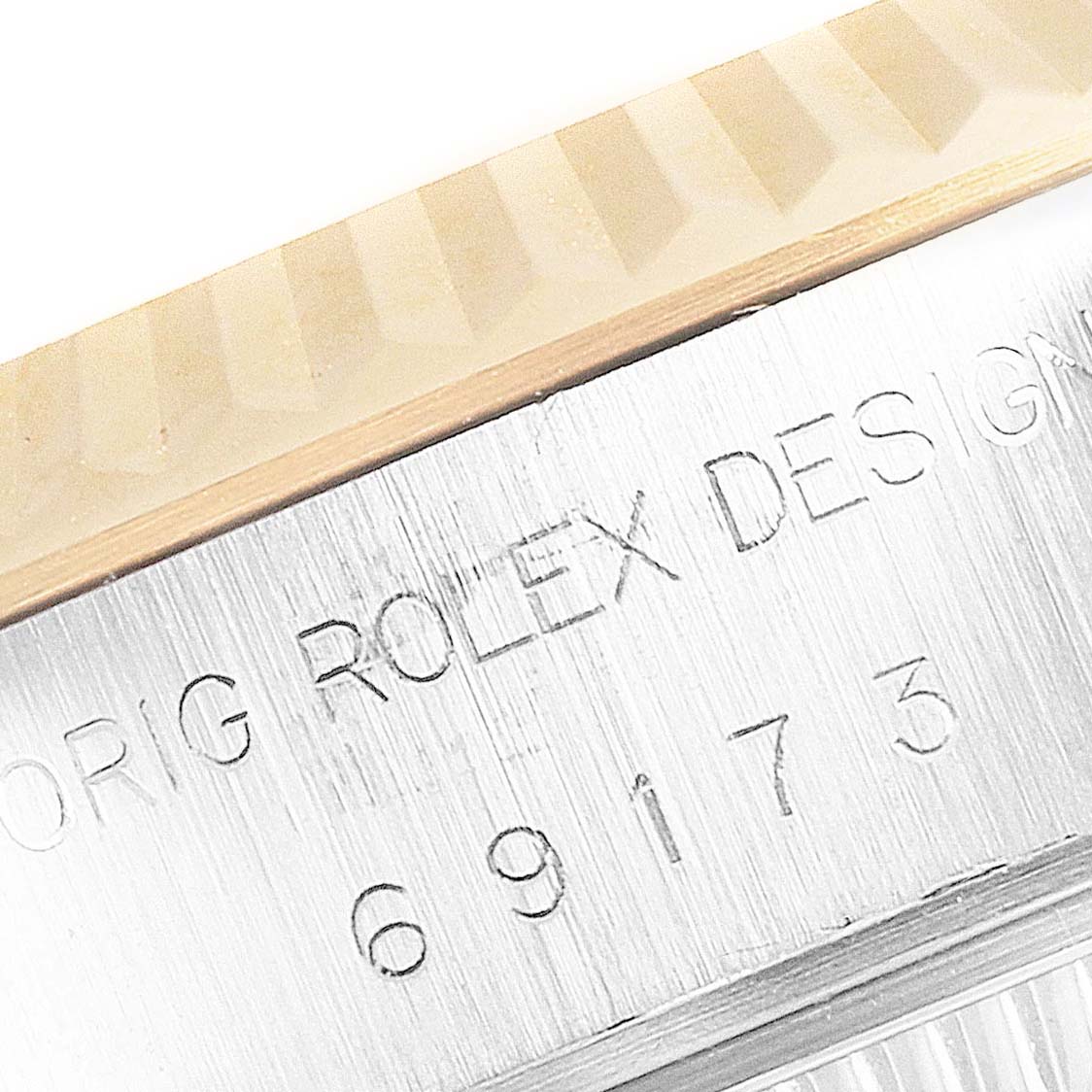 This close-up image shows the side of a Rolex Datejust 69173 Women's Steel and Gold (two tone) Champagne Dial 69173 Women's Steel and Gold (two tone) Champagne Dial model, highlighting its engraved case number and part of the fluted bezel.
