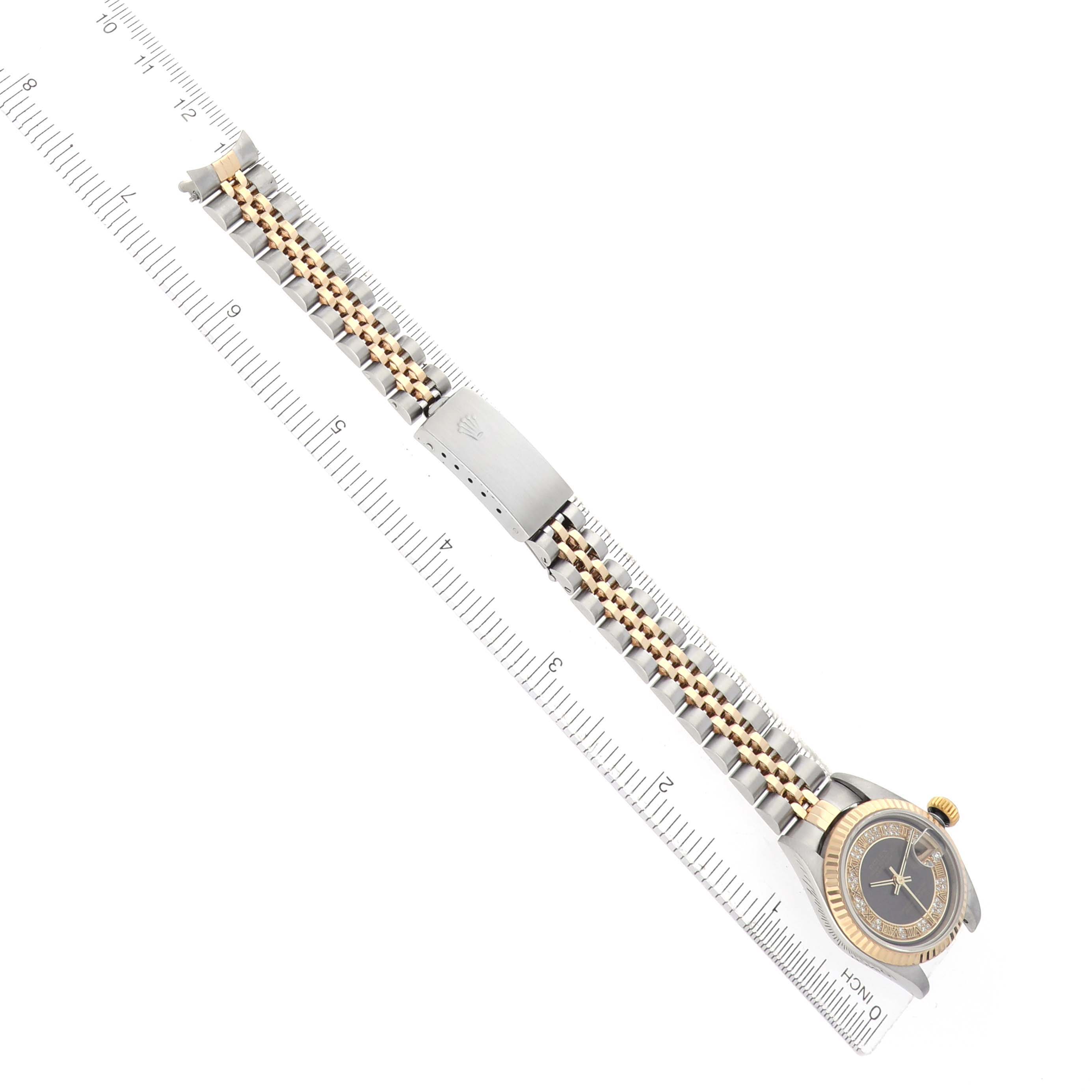 The Rolex Datejust 79173 Women
s Steel and Gold (two tone) Grey Dial watch is shown at an overhead angle, highlighting the band and clasp alongside a ruler for scale.