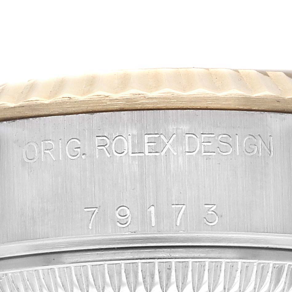 The image shows a close-up of the side and edge of the bezel on a Rolex Datejust 79173 Women
s Steel and Gold (two tone) Grey Dial, displaying engraving details.