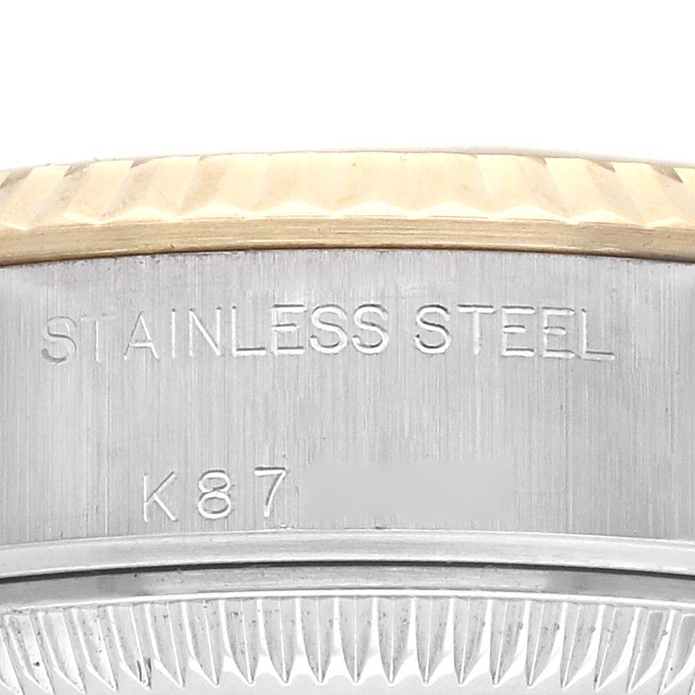 The image shows a close-up of the case side of a Rolex Datejust 79173 Women
s Steel and Gold (two tone) Grey Dial, highlighting "STAINLESS STEEL" engraving.