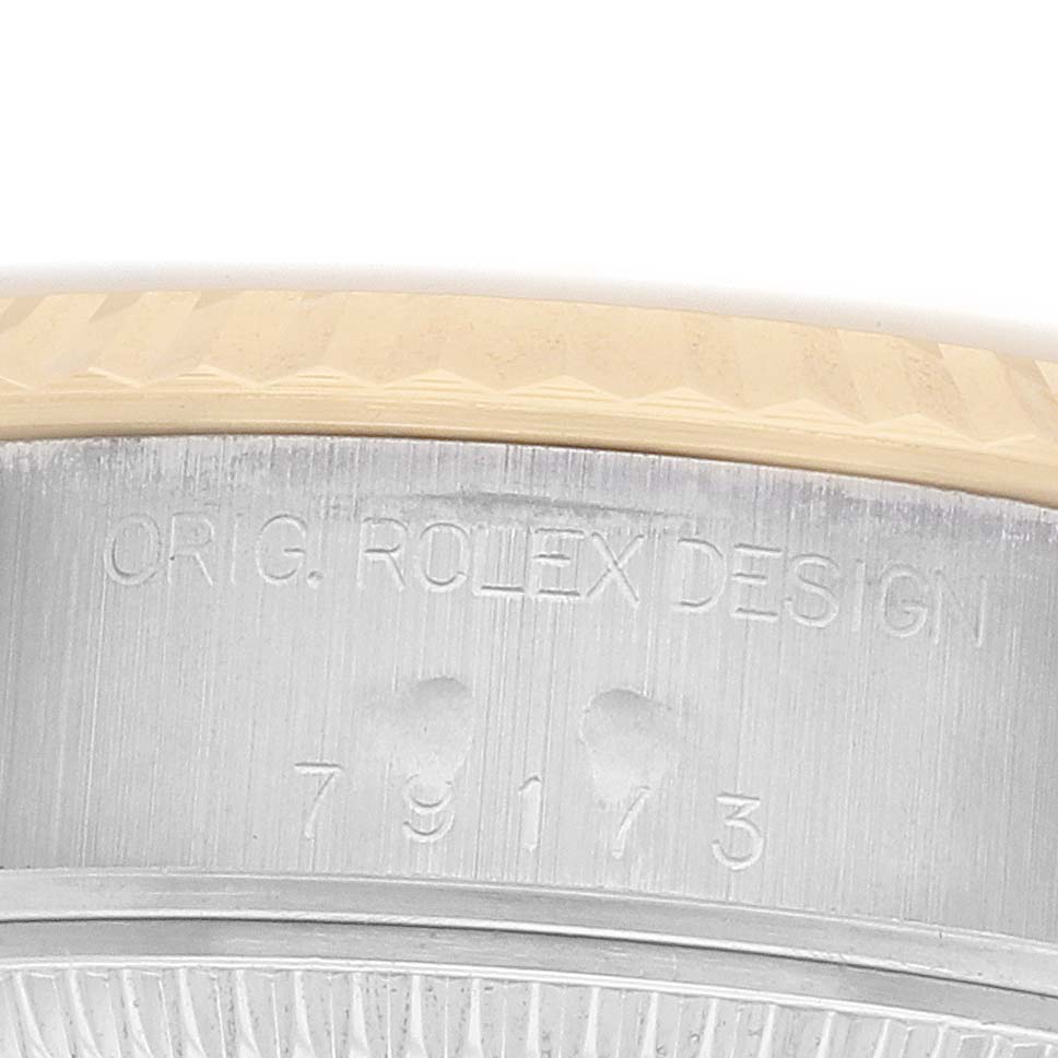 The image shows a close-up of the side of the Rolex Datejust 79173 Women
s Steel and Gold (two tone) Champagne Dial, highlighting the bezel and engraved design details.