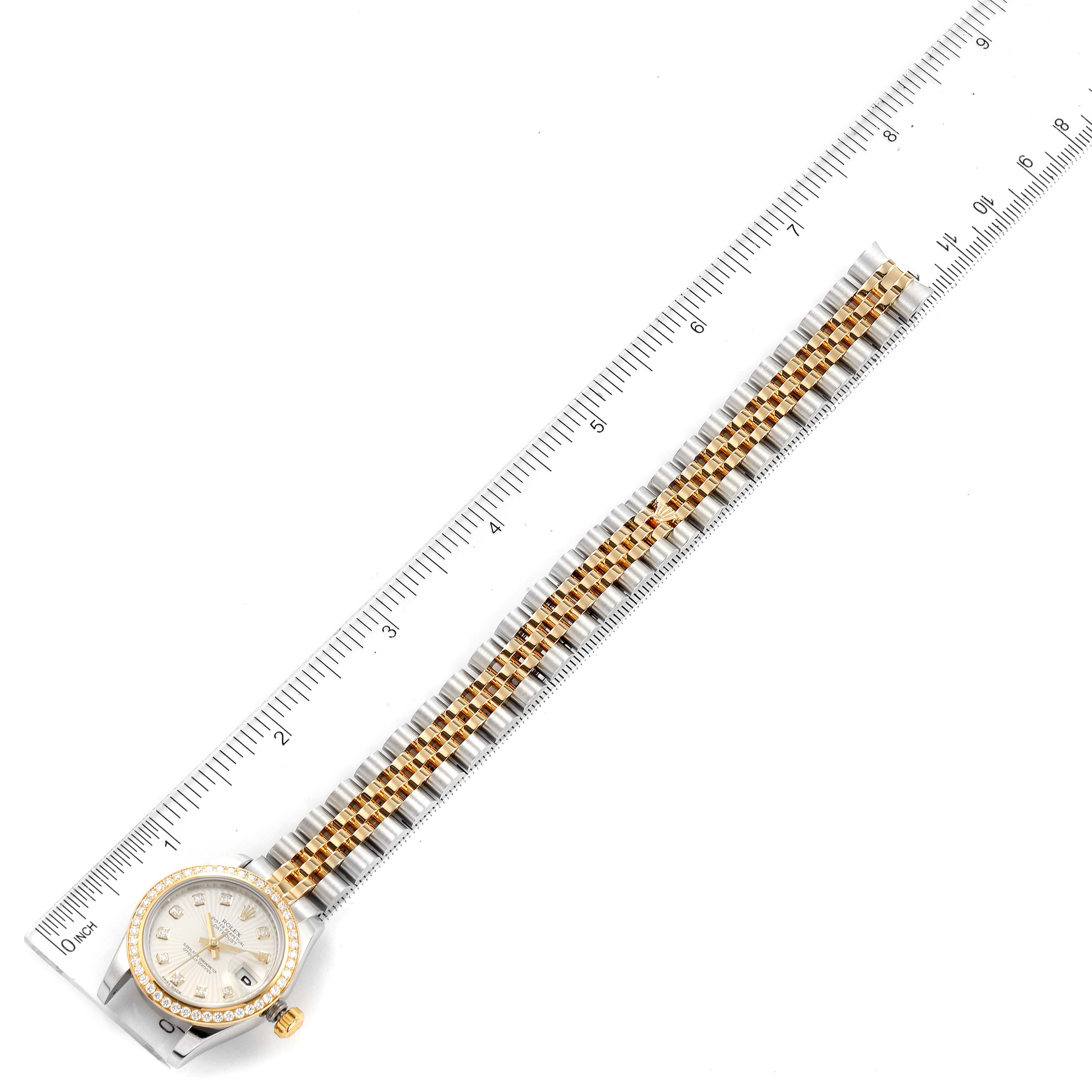 The image shows a top-down view of a Rolex Datejust 179383 Women
s Steel and Gold (two tone) Silver Dial 179383 Women
s Steel and Gold (two tone) Silver Dial watch, displaying its dial, bezel, and two-tone bracelet alongside a ruler.