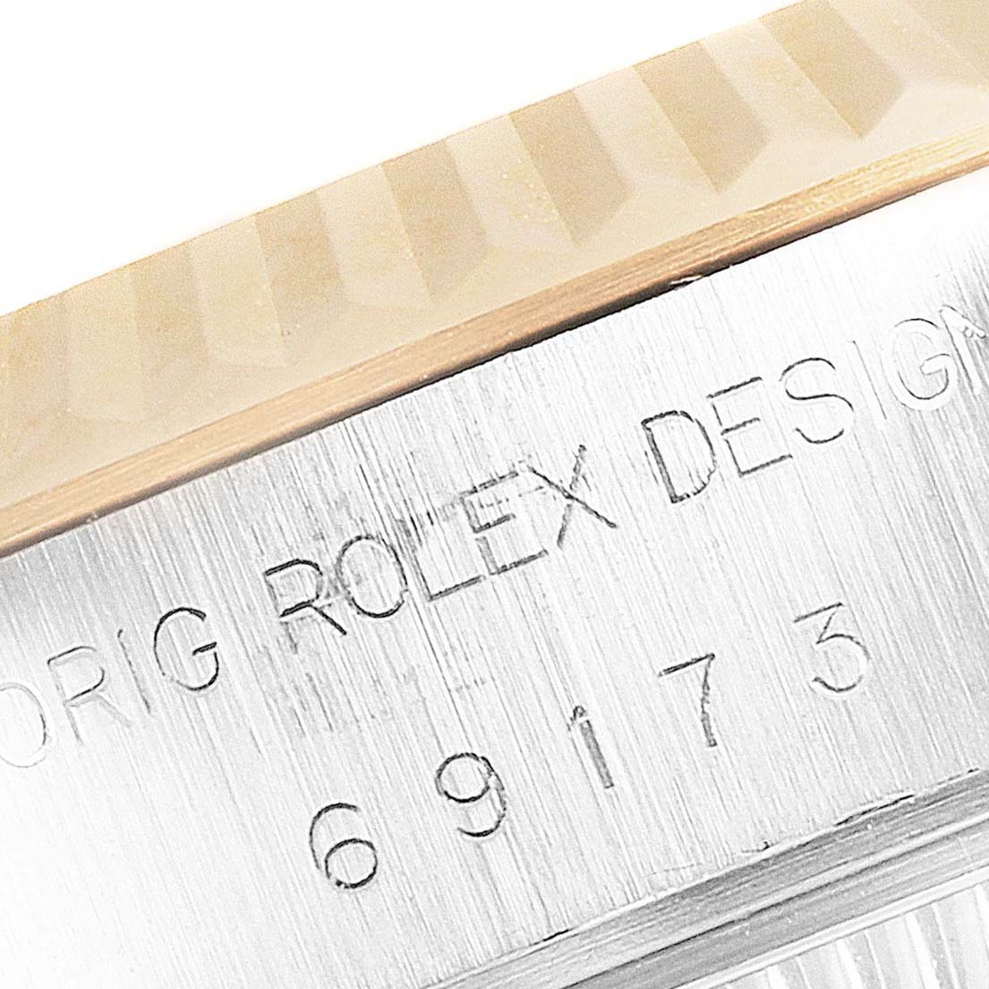 The image shows a close-up of the side engraving and fluted bezel of a Rolex Datejust 69173 Women's Steel and Gold (two tone) White Dial 69173 Women's Steel and Gold (two tone) White Dial watch.