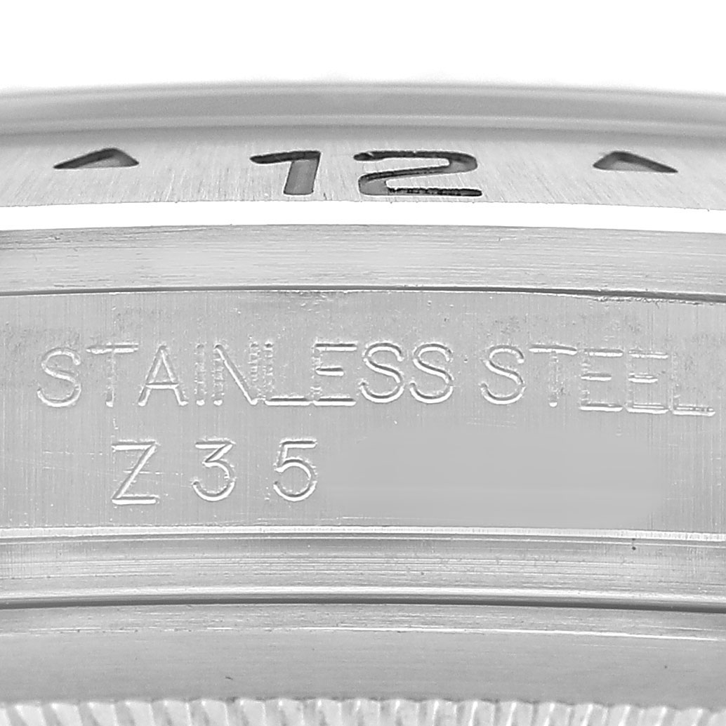 The image shows a close-up of the side of a Rolex Explorer 16570 Men's Stainless Steel Black Dial watch, focusing on the engraved "STAINLESS STEEL" marking.