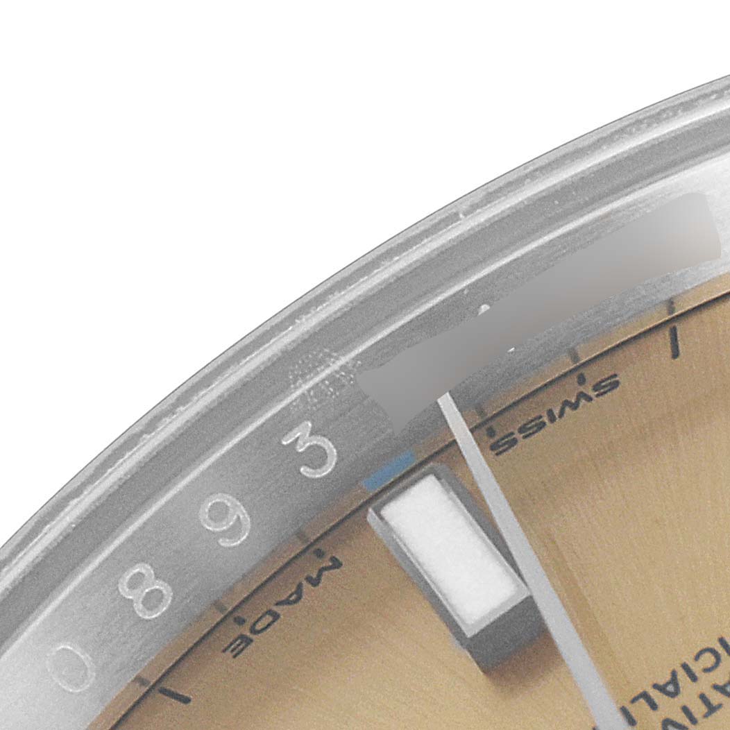 This image shows a close-up of the bezel and a portion of the dial of a Rolex Oyster Perpetual 114200 Men's Stainless Steel Champagne Dial 114200 Men's Stainless Steel Champagne Dial watch.