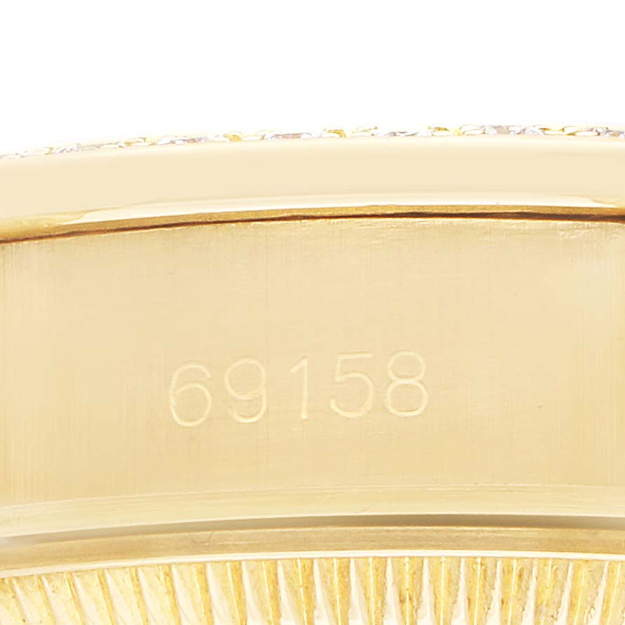 The image shows a close-up of the side of a Rolex President 69158 Women
s Yellow Gold Champagne Dial model watch, focusing on the engraved serial number on the case.