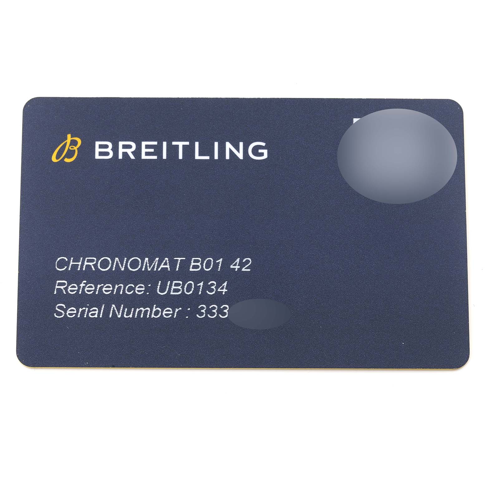 A Breitling Chronomat UB0134 Men's Steel and Gold (two tone) Grey Dial UB0134 Men's Steel and Gold (two tone) Grey Dial model card showing the brand logo, model number, reference, and serial number from a top-down angle.