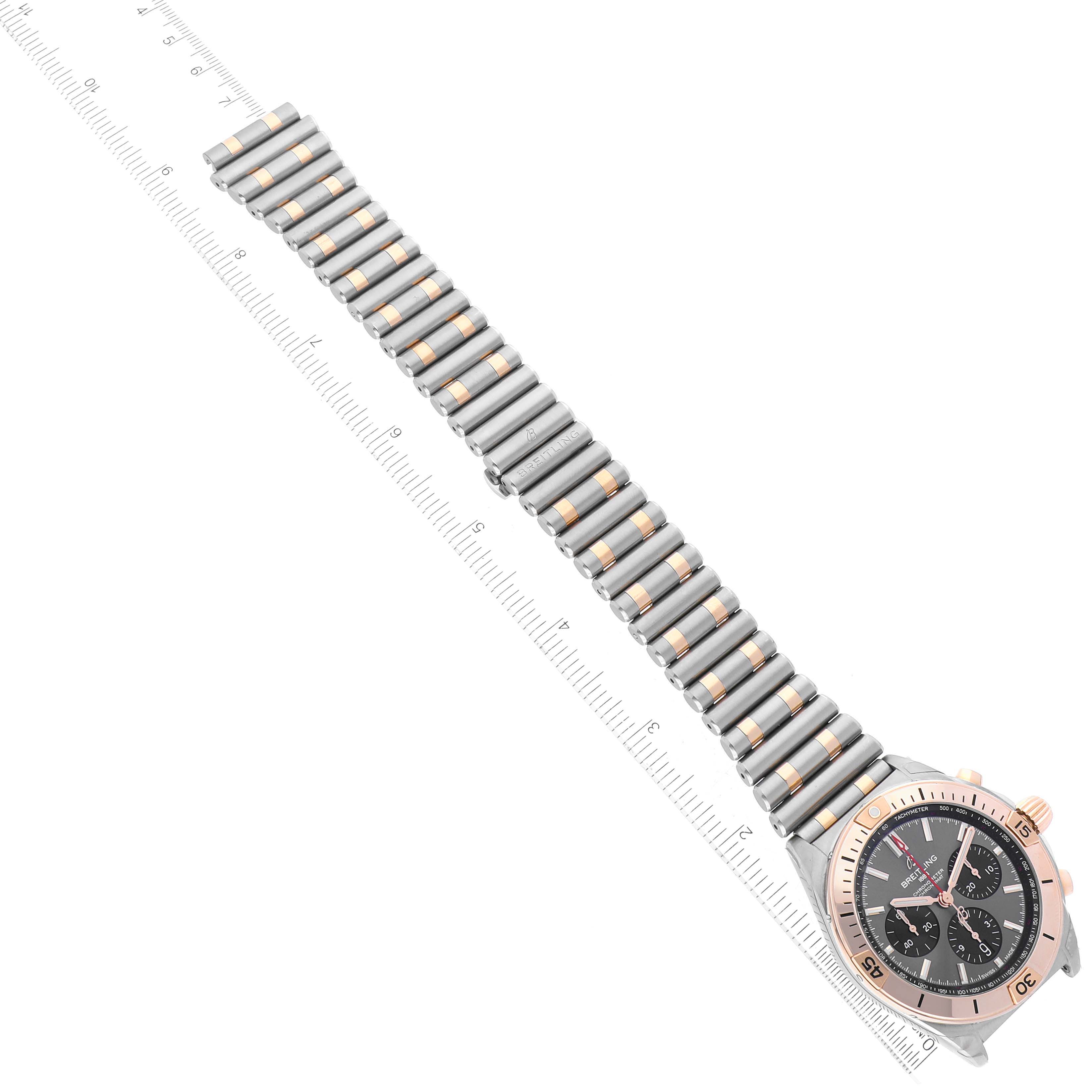 This image shows a Breitling Chronomat UB0134 Men's Steel and Gold (two tone) Grey Dial UB0134 Men's Steel and Gold (two tone) Grey Dial watch laid out horizontally with the bracelet and partial bezel visible, alongside a ruler for measurement.