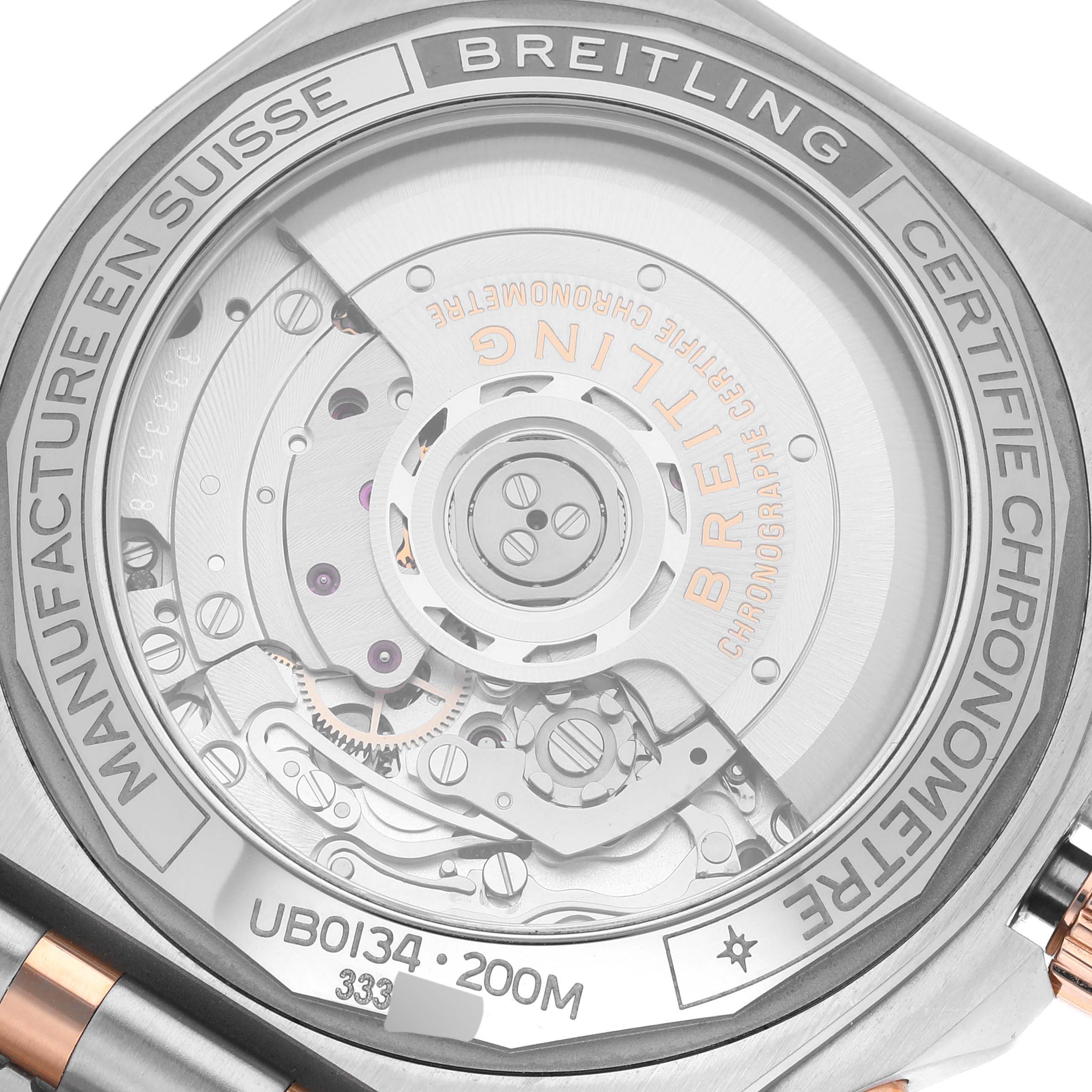 The image shows a close-up of the Breitling Chronomat UB0134 Men's Steel and Gold (two tone) Grey Dial UB0134 Men's Steel and Gold (two tone) Grey Dial's case back, revealing part of the internal movement and inscriptions.