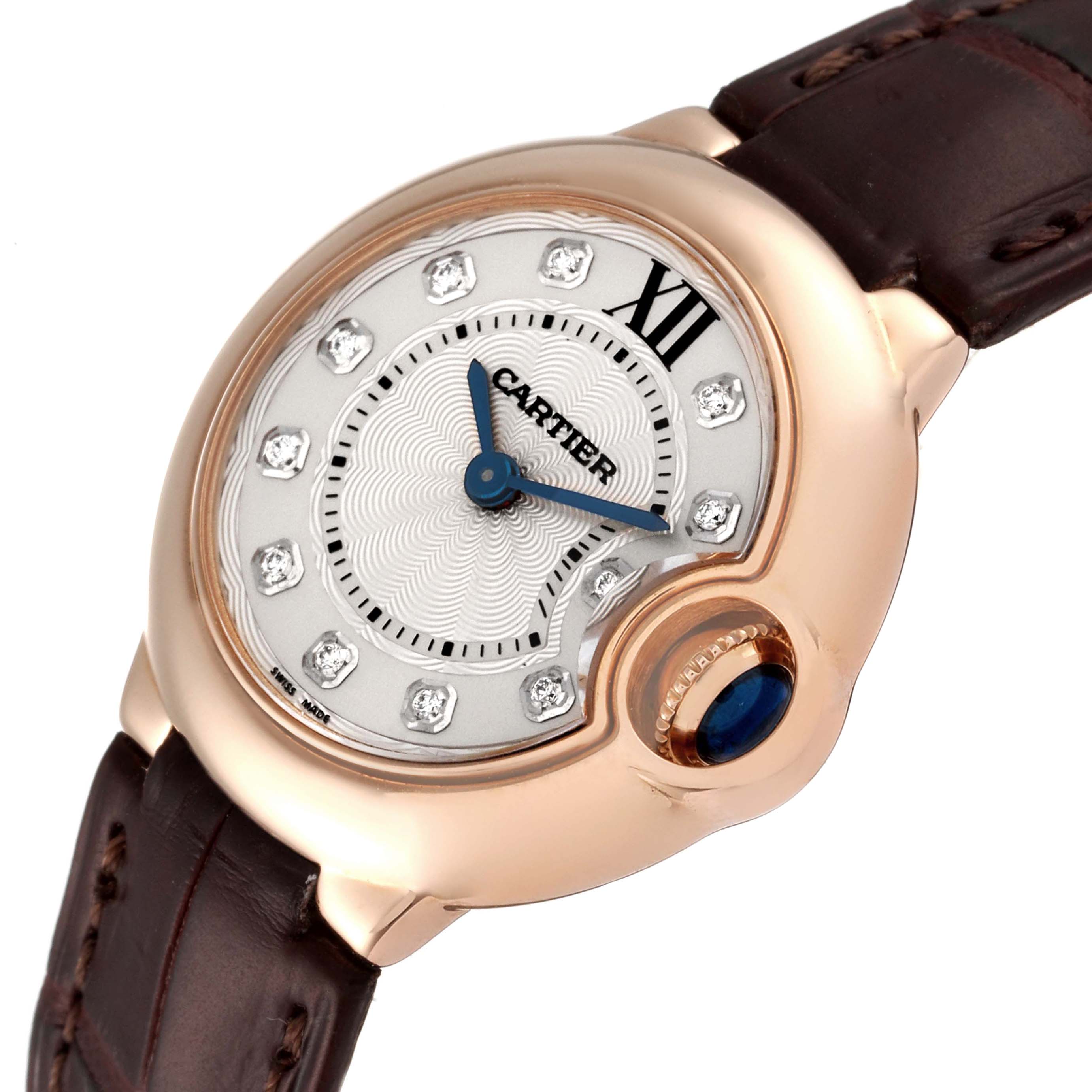 The image shows a close-up view of the Cartier Ballon Bleu WE902050 Women's Rose Gold Silver Dial WE902050 Women's Rose Gold Silver Dial watch face and part of the leather strap, highlighting the crown and signature elements.