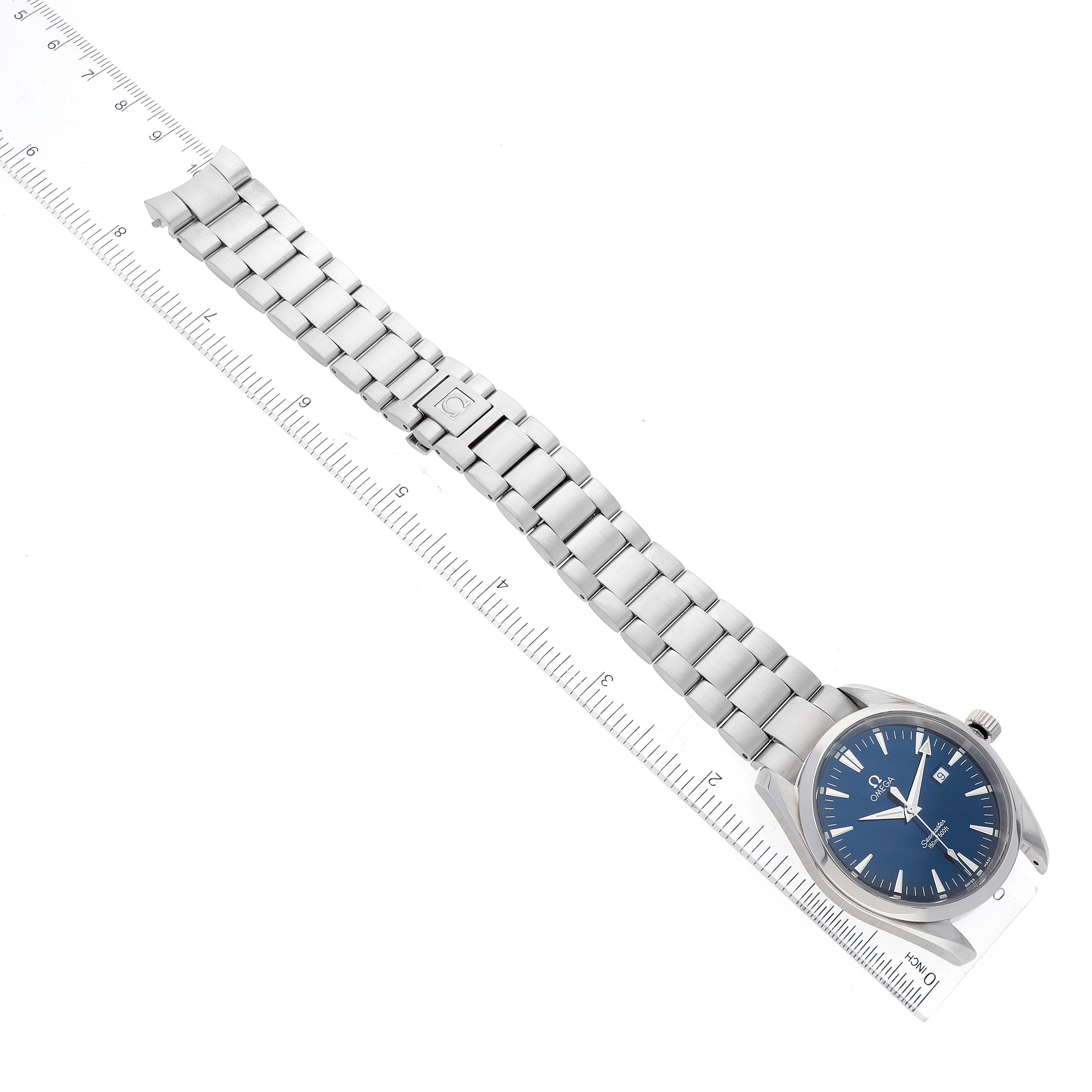 The image shows an Omega Aqua Terra 2517.80.00 Men's Stainless Steel Blue Dial 2517.80.00 Men's Stainless Steel Blue Dial watch with a blue dial and metal bracelet, viewed from a top angle, placed on a ruler.