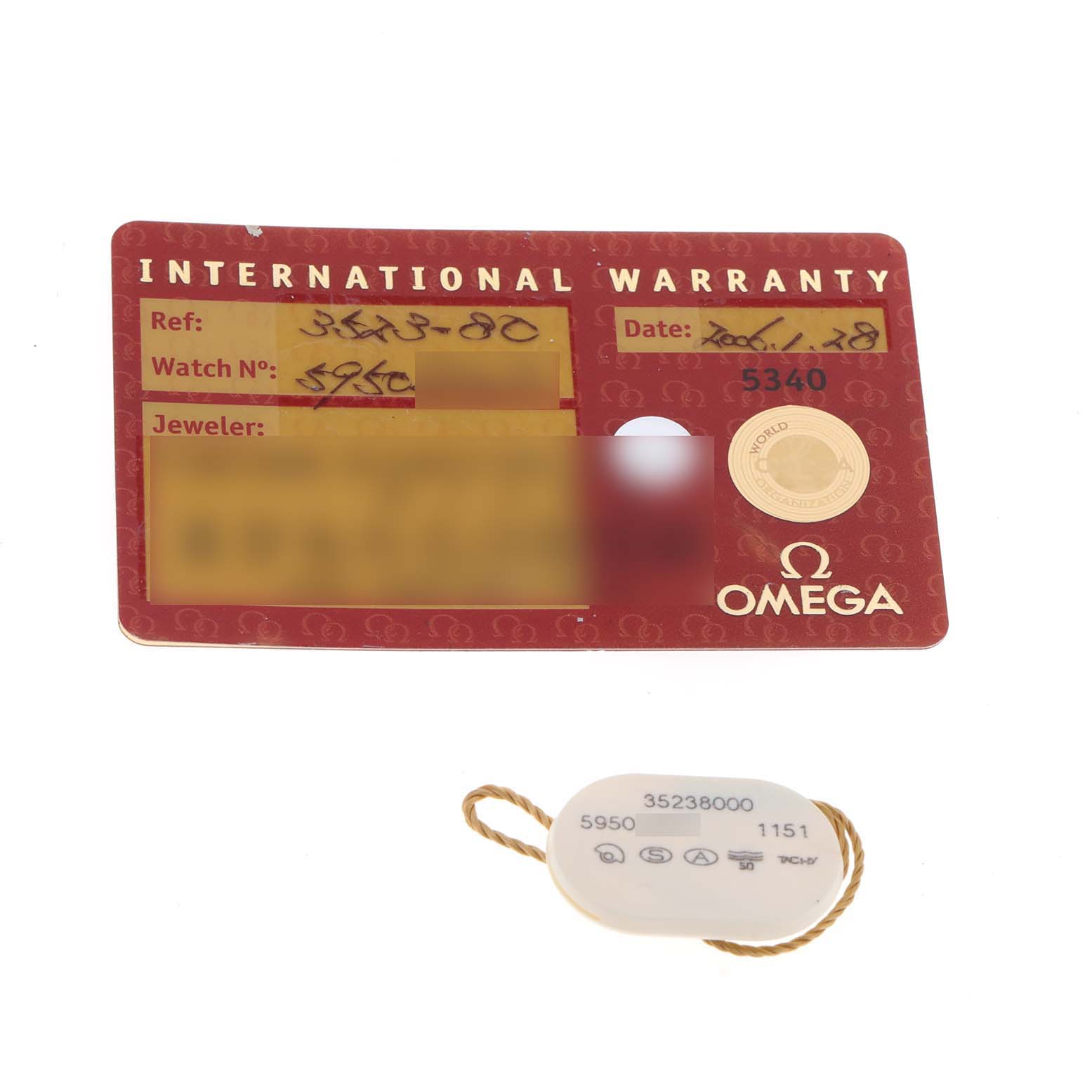 The image shows the International Warranty card and a tag for the Omega Speedmaster 3523.80.00 Men
s Stainless Steel Blue Dial 3523.80.00 Men
s Stainless Steel Blue Dial watch.