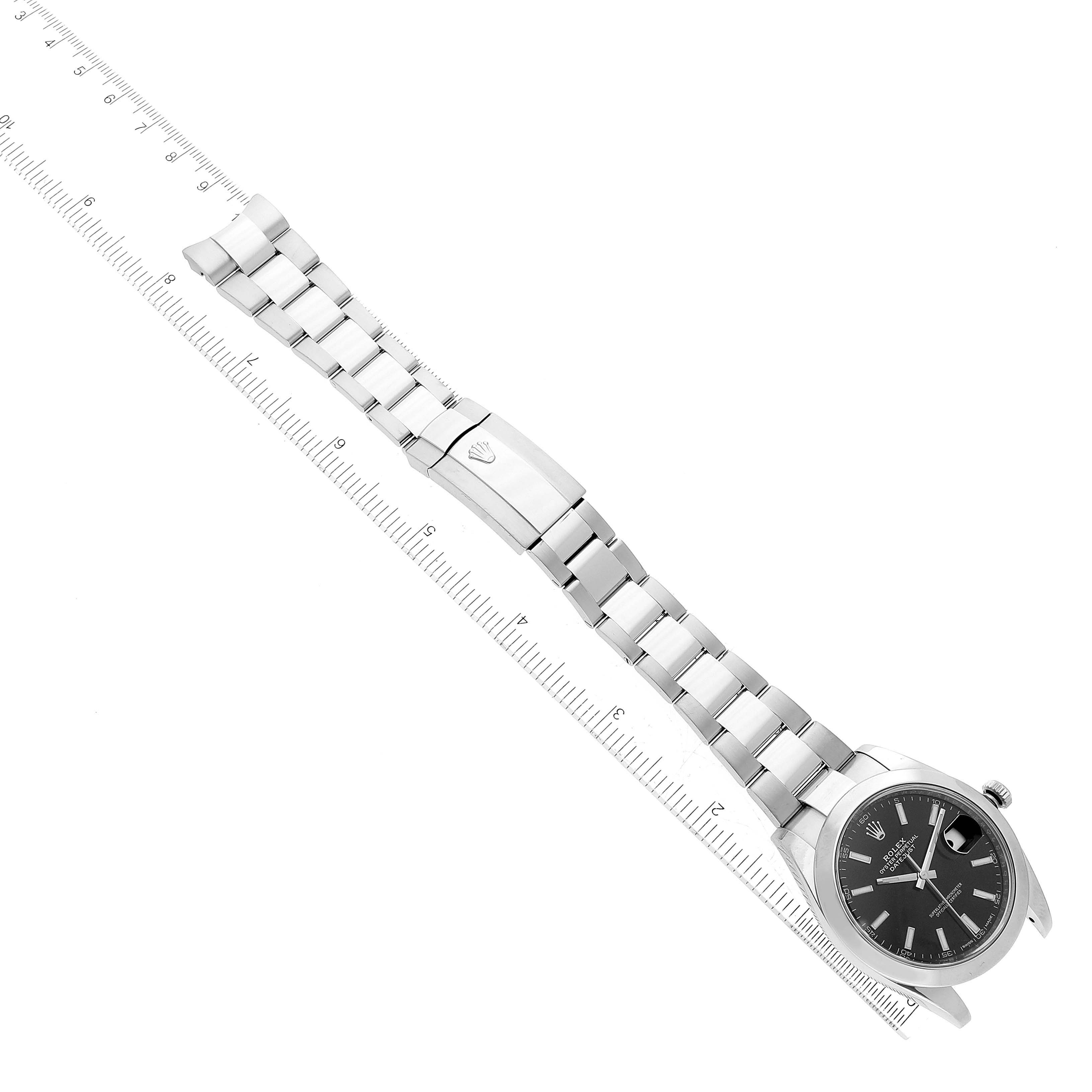 The image shows a top-down view of a Rolex Datejust 41 126300 Men
s Stainless Steel Black Dial 126300 Men
s Stainless Steel Black Dial watch with its stainless steel bracelet extended alongside a measuring ruler.