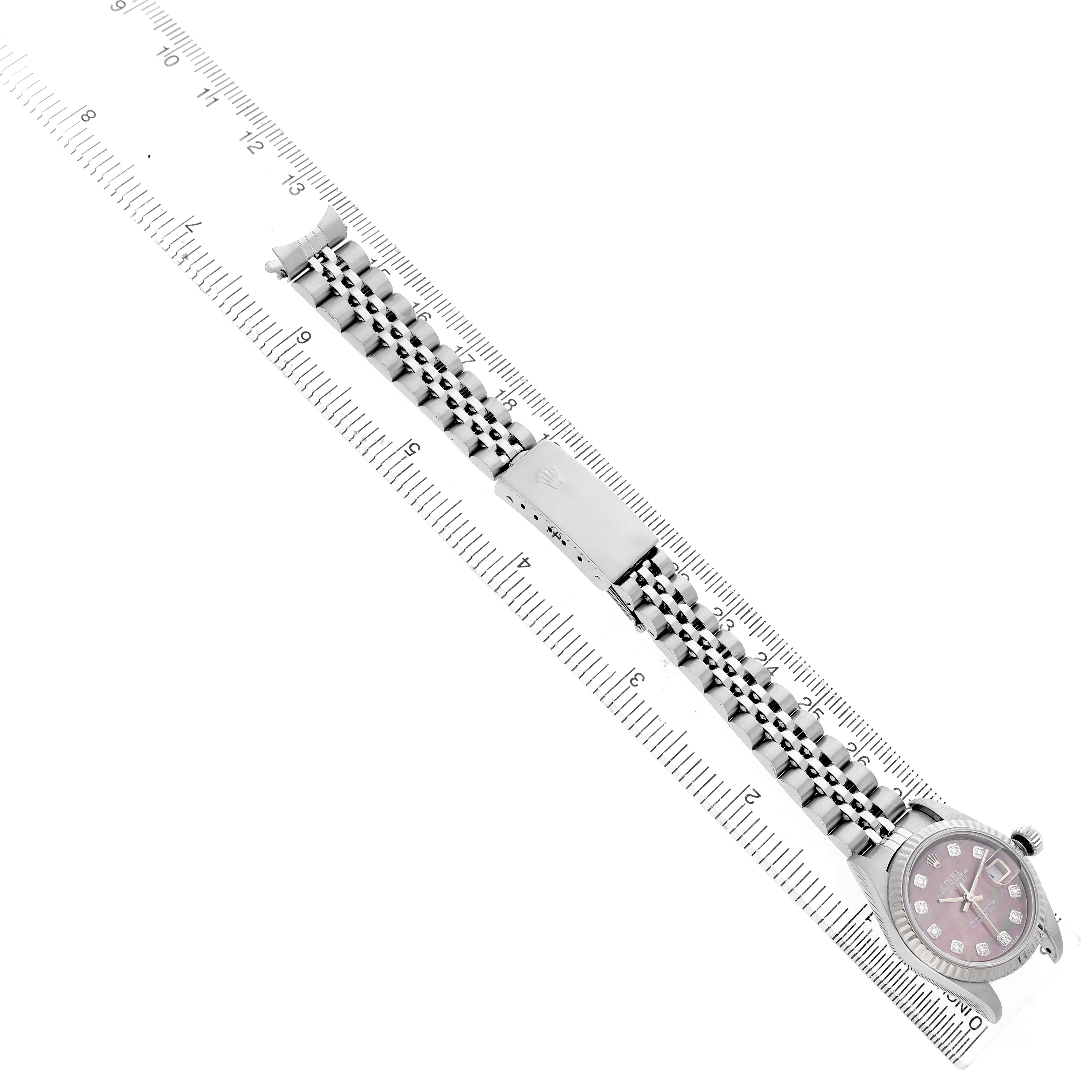 The Rolex Datejust 79174 Women's Stainless Steel Mother of Pearl Dial watch is shown at an angle displaying the full bracelet, clasp, and face with a ruler for scale.