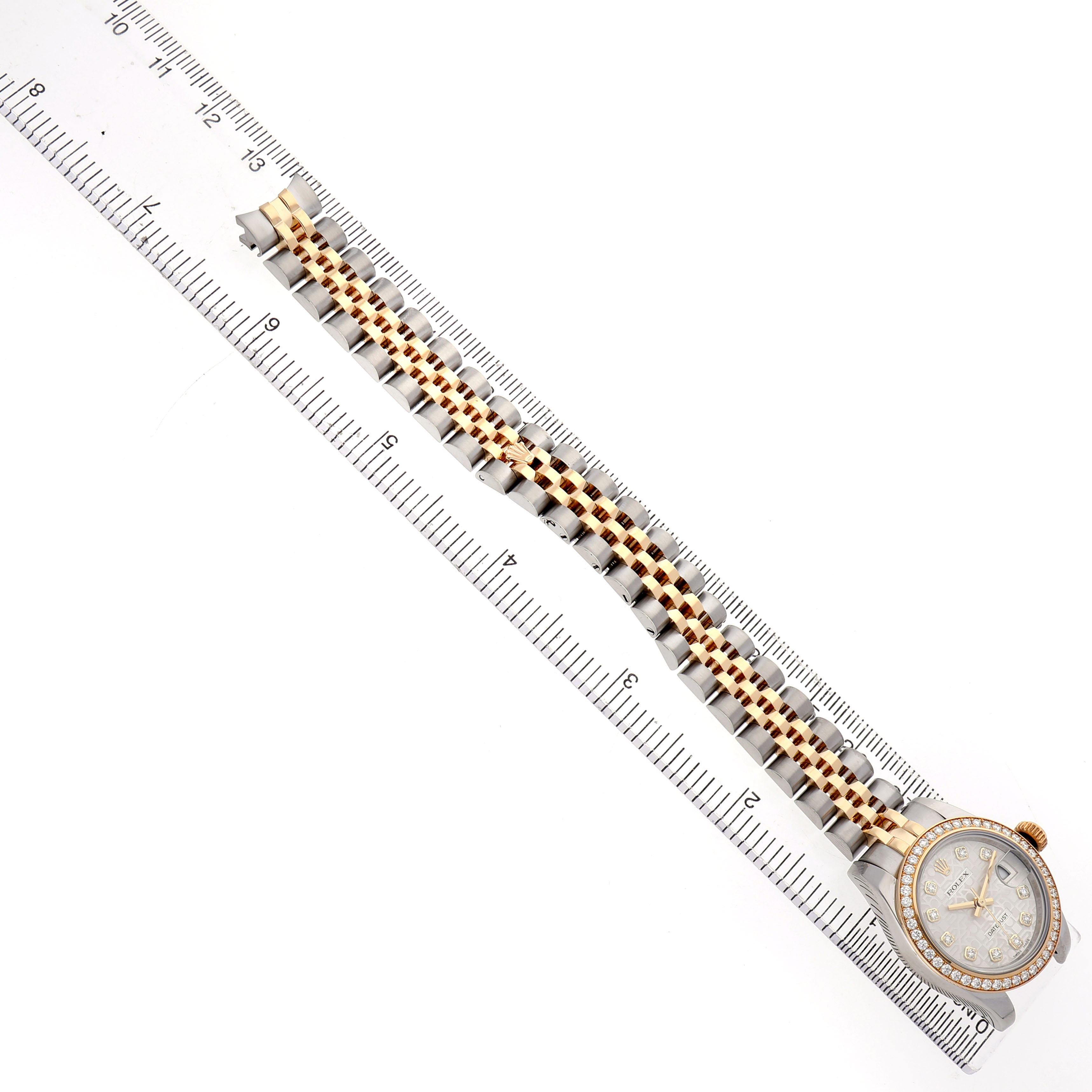 The Rolex Datejust 179383 Women's Steel and Gold (two tone) Silver Dial watch is shown from a top view, displaying the face, bezel, and full bracelet alongside a measuring scale.