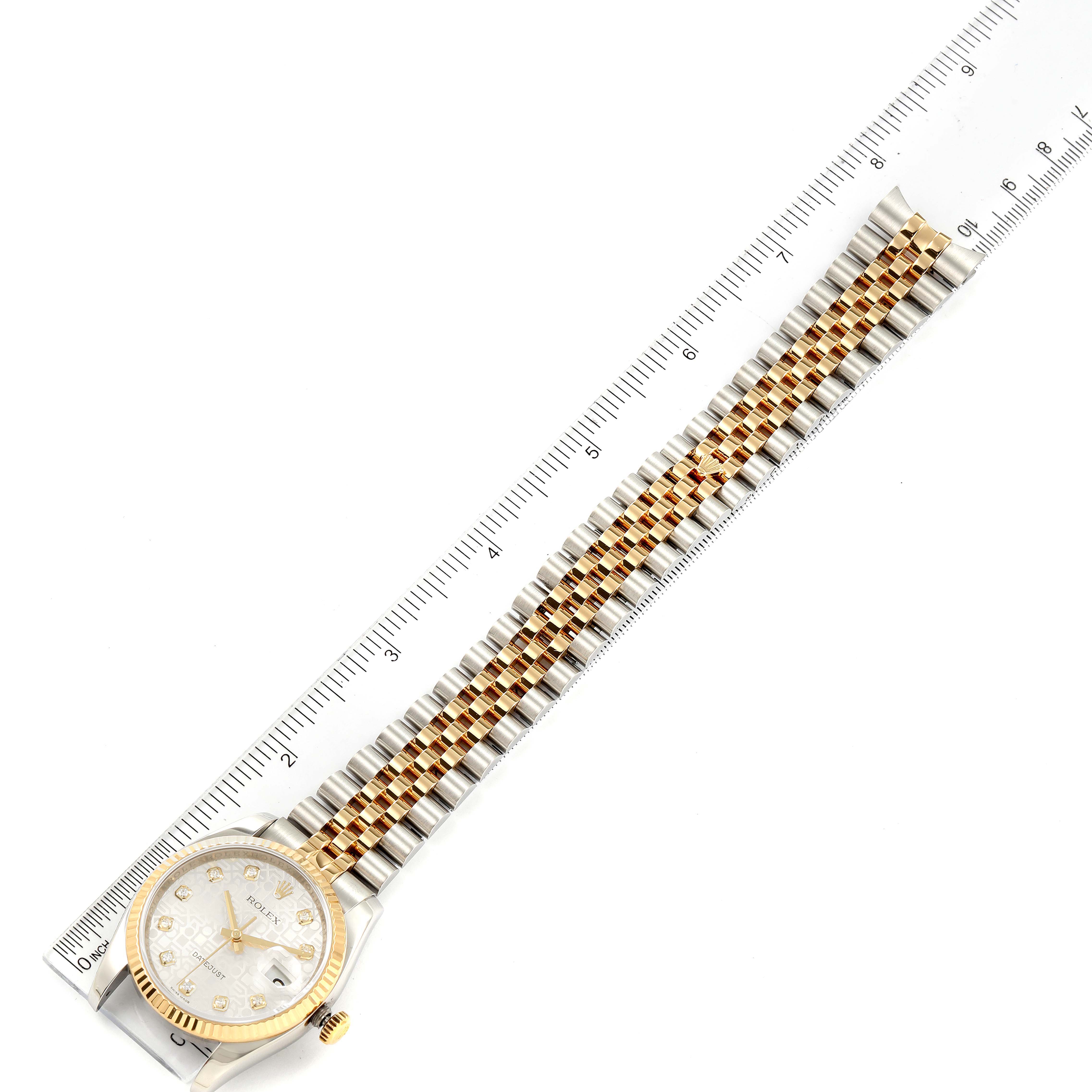 This image shows a Rolex Datejust 116233 Men's Steel and Gold (two tone) Silver Dial 116233 Men's Steel and Gold (two tone) Silver Dial watch laid flat with its gold and silver bracelet next to a ruler for measurement.
