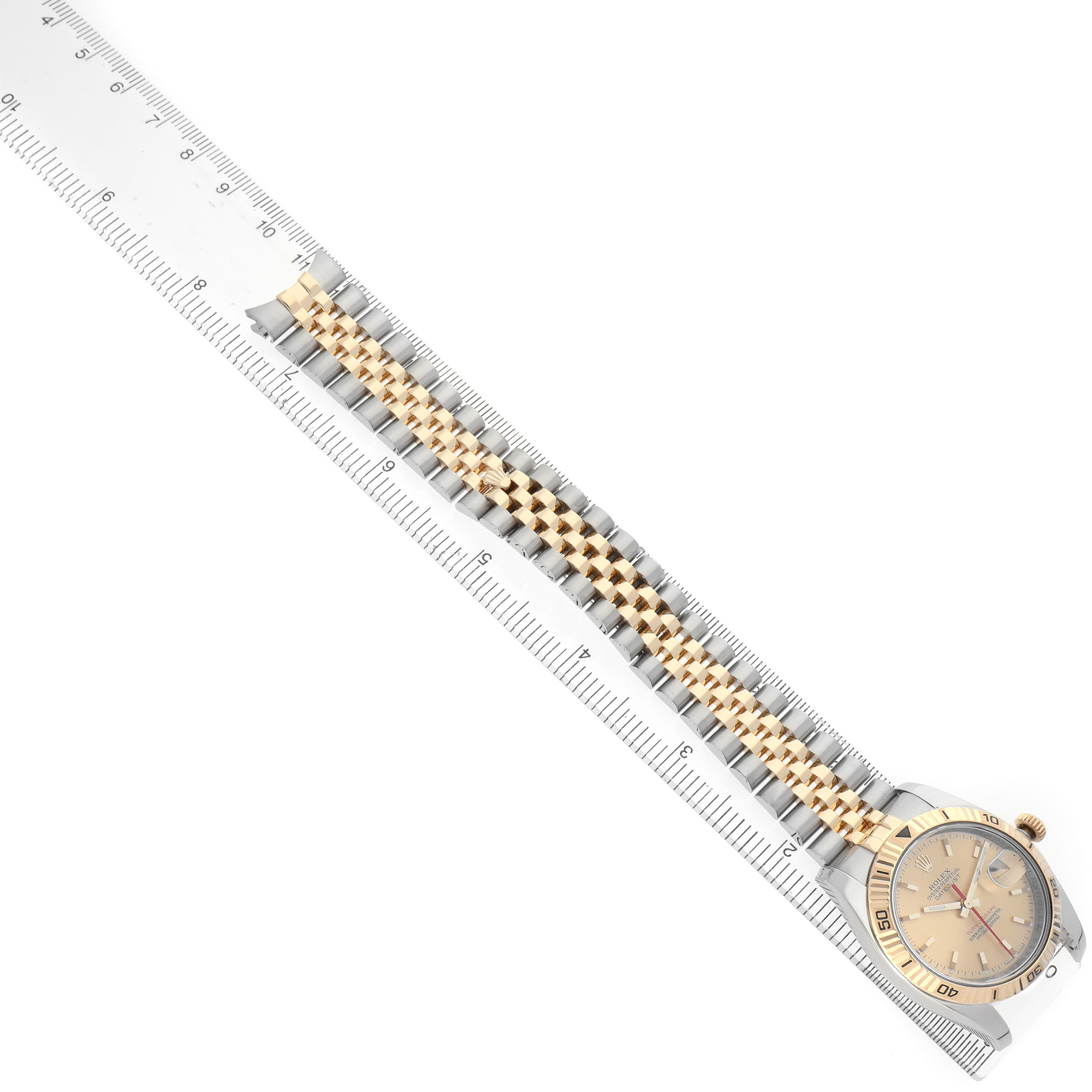The image shows a Rolex Turn-o-Graph 116263 Men's Steel and Gold (two tone) Champagne Dial watch laid flat with a focus on the face and bracelet against a ruler.