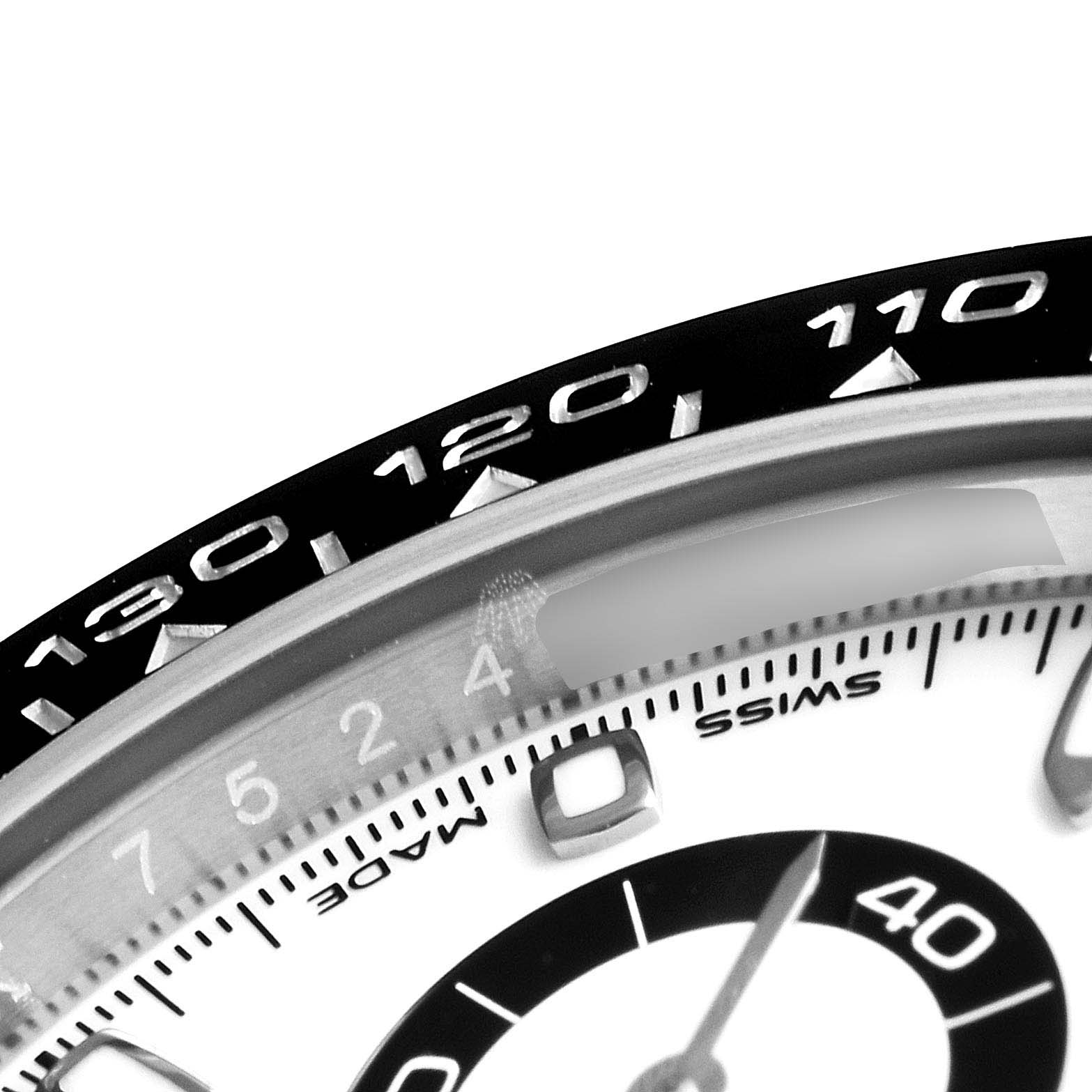 The image shows a close-up of the bezel and part of the dial of a Rolex Daytona 116500 Men's Stainless Steel White Dial 116500 Men's Stainless Steel White Dial watch.