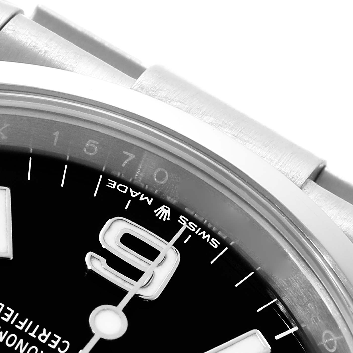 The image shows a close-up of the upper part of the dial and bezel of a Rolex Explorer 124270 Men
s Stainless Steel Black Dial 124270 Men
s Stainless Steel Black Dial watch, highlighting the 
Swiss Made
 label and part of the bracelet.