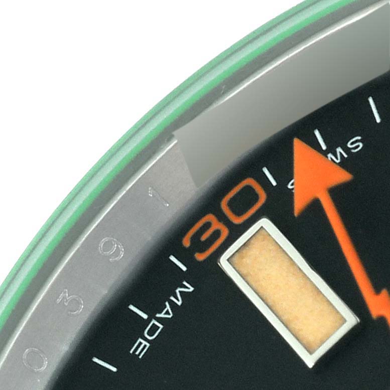 This close-up image of the Rolex Milgauss 116400 Men's Stainless Steel Black Dial 116400 Men's Stainless Steel Black Dial watch shows the minute markings, part of the orange arrow hand, and the edge of the green-tinted crystal.