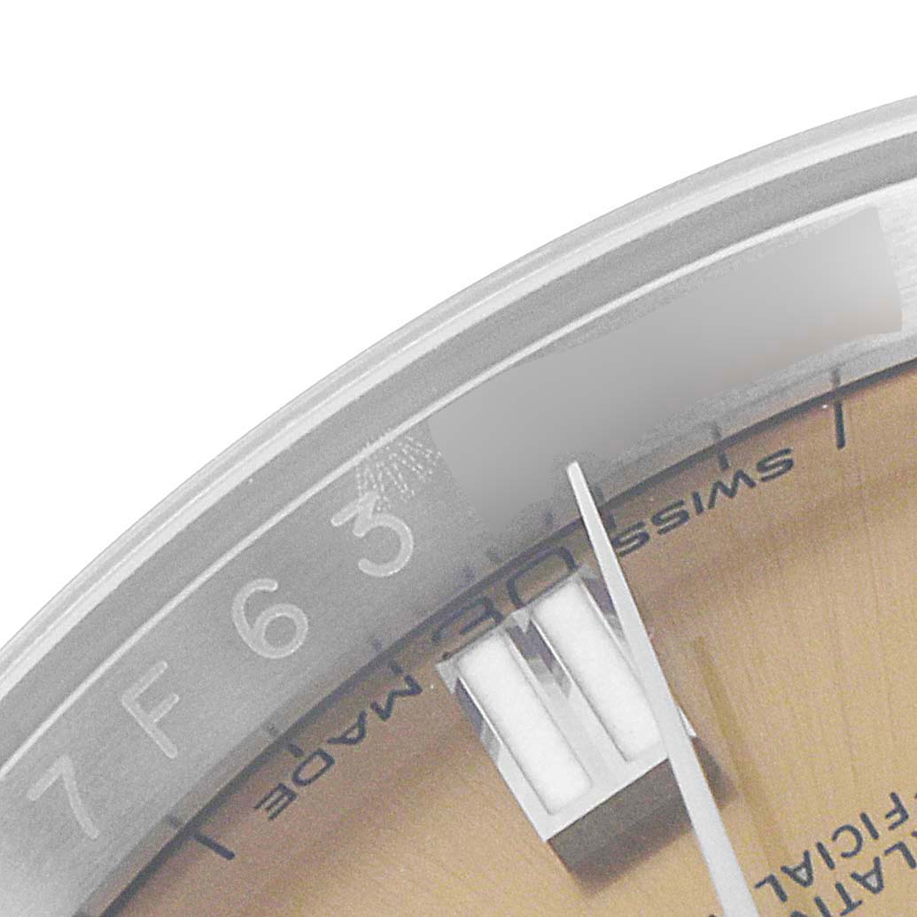The image shows a close-up angle of the dial and part of the bezel of a Rolex Oyster Perpetual 116000 Men's Stainless Steel Champagne Dial 116000 Men's Stainless Steel Champagne Dial watch.