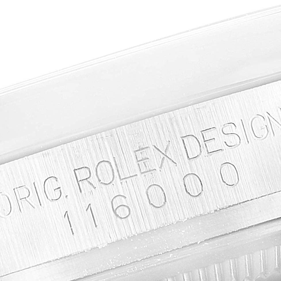 This image shows a close-up angle of the engraved bezel of a Rolex Oyster Perpetual 116000 Men's Stainless Steel Champagne Dial 116000 Men's Stainless Steel Champagne Dial watch, model number 116000.
