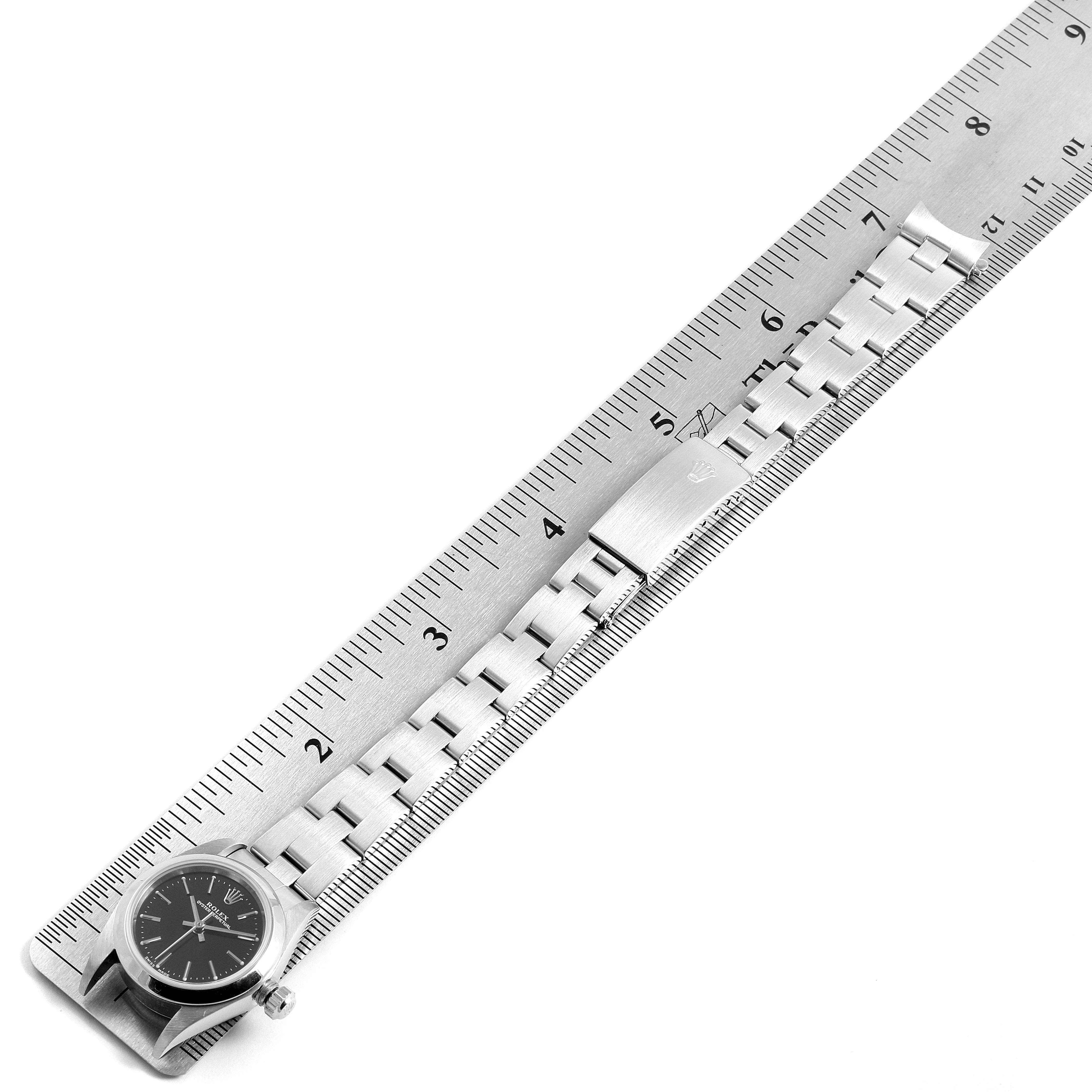 The image shows the full length of a Rolex Oyster Perpetual 76080 Women's Stainless Steel Black Dial 76080 Women's Stainless Steel Black Dial watch alongside a ruler.
