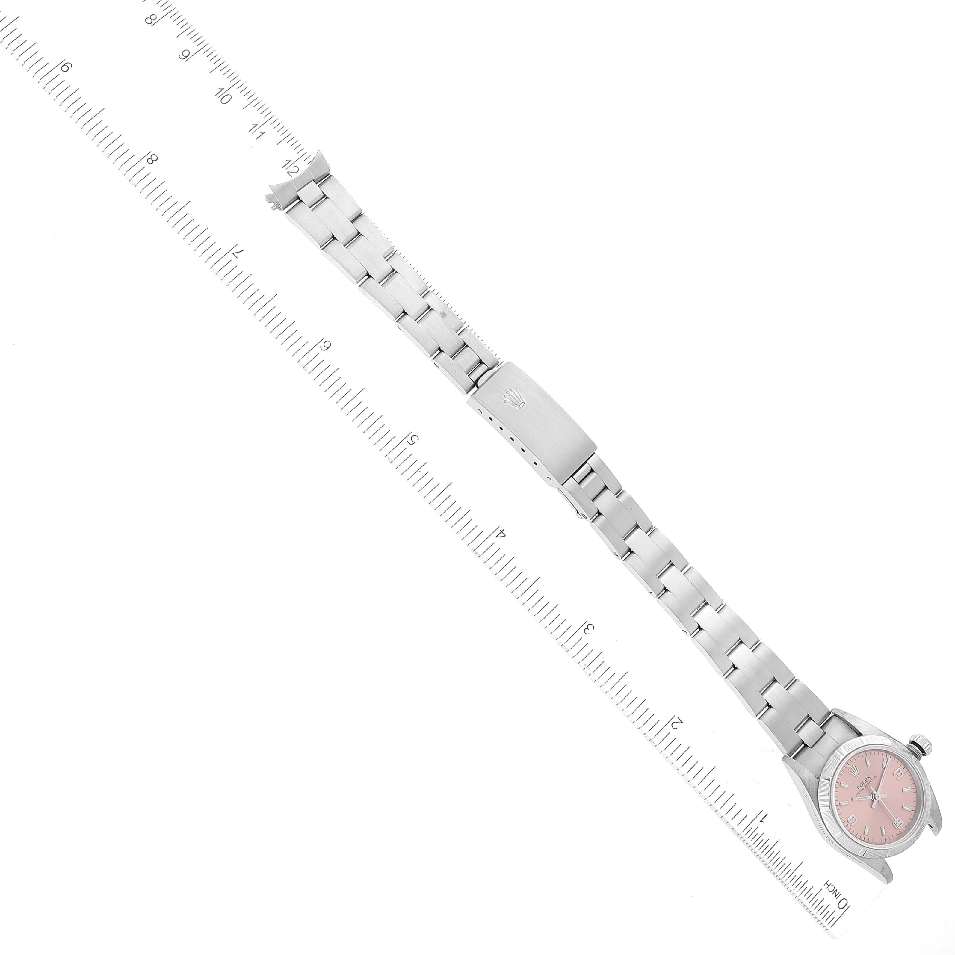 The image shows a Rolex Oyster Perpetual 76030 Women
s Stainless Steel Pink Dial 76030 Women
s Stainless Steel Pink Dial watch laid flat, fully extended, with a ruler for scale.