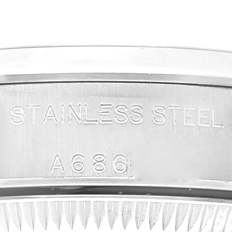 This close-up shows the side of the Rolex Oyster Perpetual 76080 Women
s Stainless Steel Pink Dial 76080 Women
s Stainless Steel Pink Dial watch case with the "STAINLESS STEEL" engraving and a partial serial number.