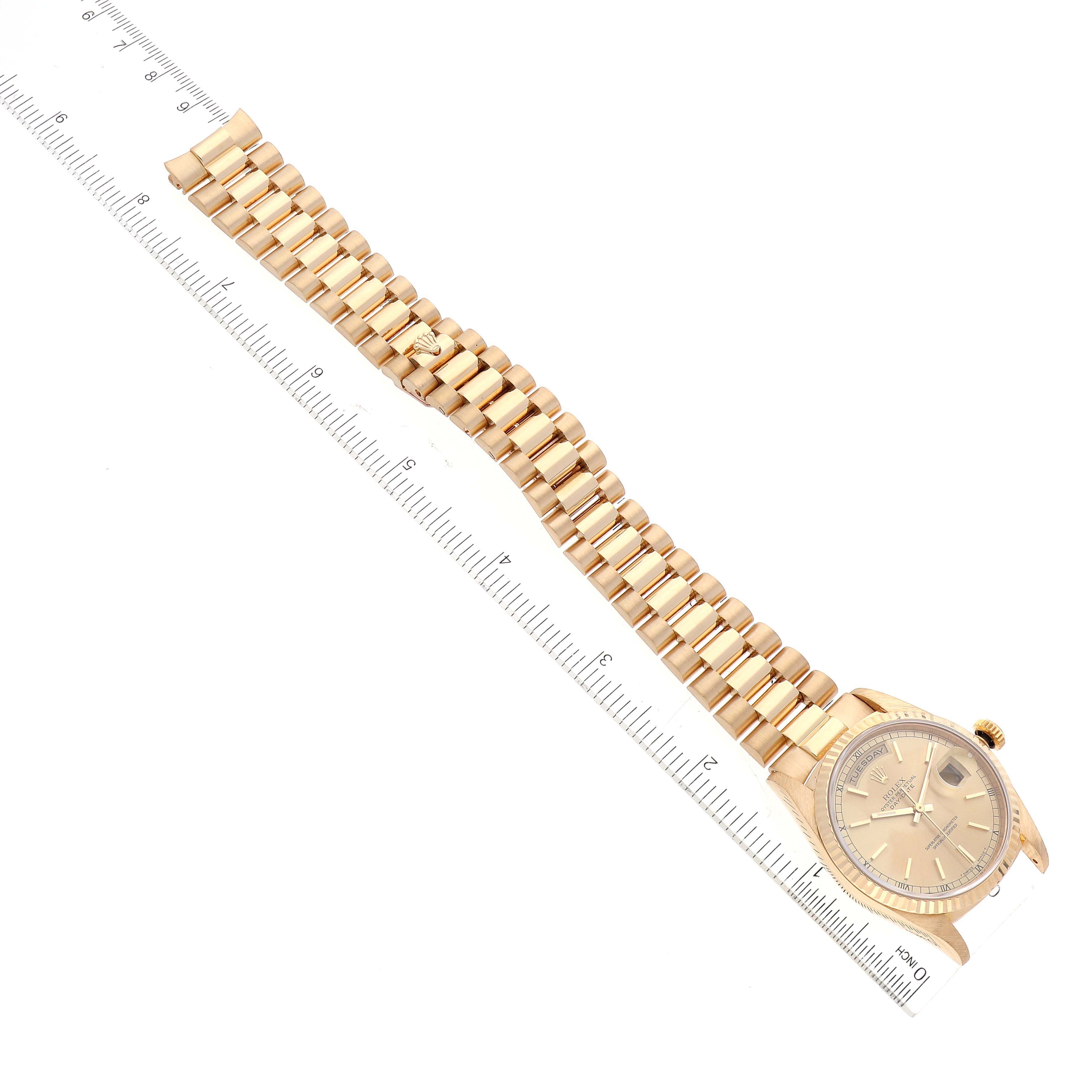 The image shows the full length of a Rolex President 18238 Men
s Yellow Gold Champagne Dial 18238 Men
s Yellow Gold Champagne Dial model watch with a focus on the face and gold bracelet, measured against a ruler.