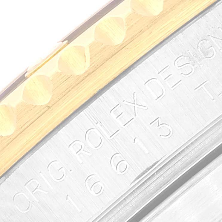 The image shows a close-up angle of a Rolex Submariner 16613 Men
s Steel and Gold (two tone) Blue Dial 16613 Men
s Steel and Gold (two tone) Blue Dial watch band, focusing on the engraved model number and part of the bezel.
