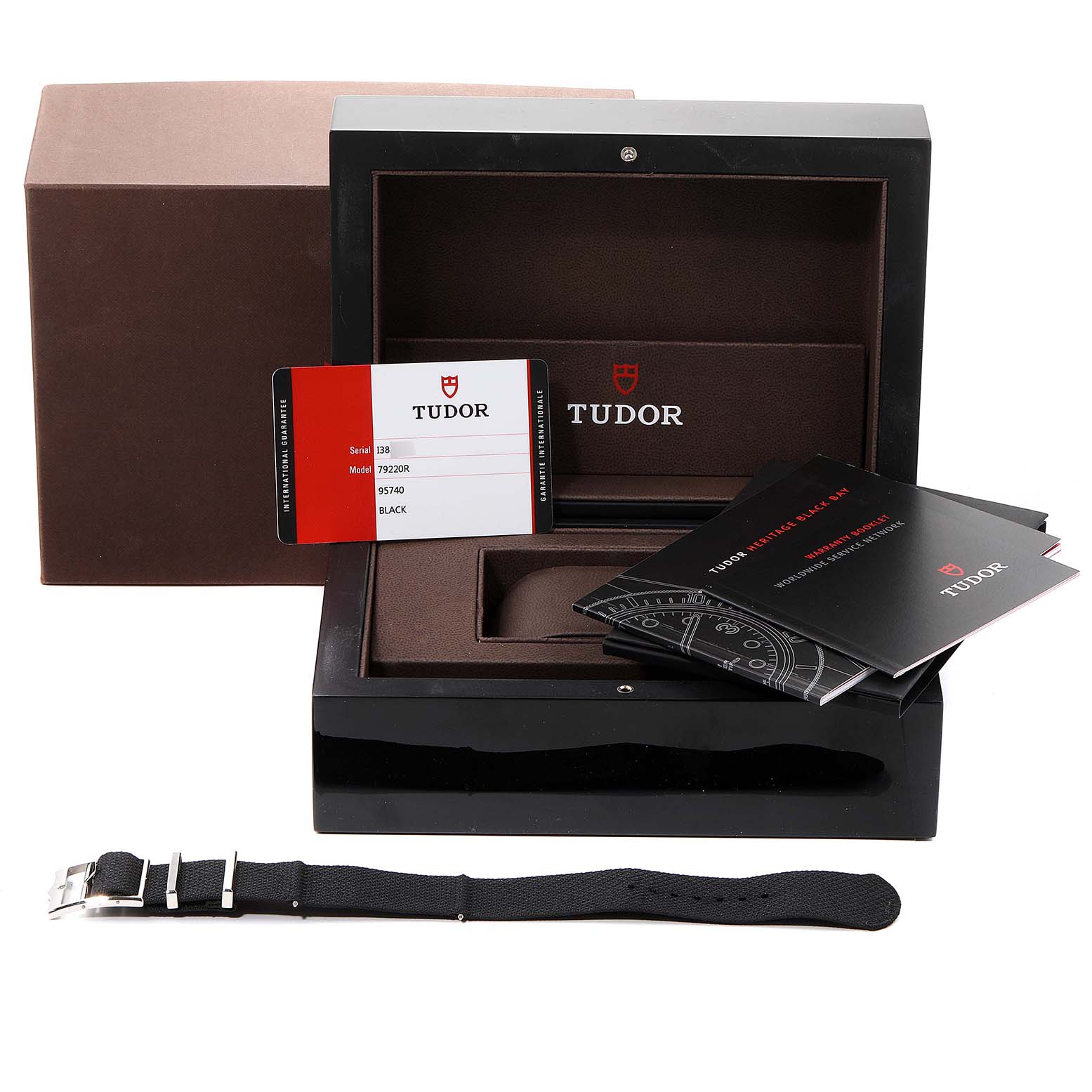 The image shows an open Tudor Heritage Black Bay 79220R Men's Stainless Steel Black Dial 79220R Men's Stainless Steel Black Dial watch box, accompanying manuals, a guarantee card, and an extra strap.