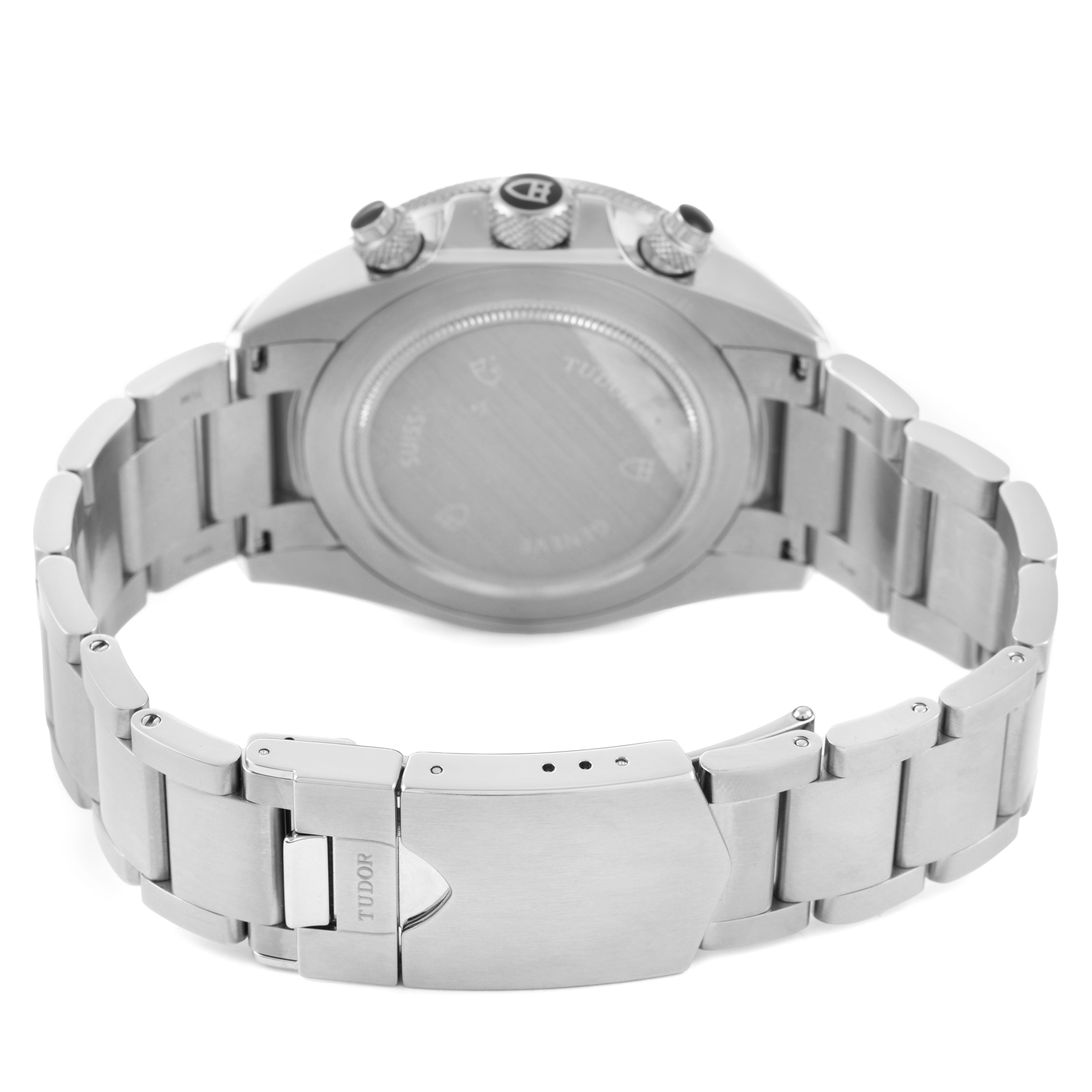The Tudor Heritage Chrono 70330N-65740 Men's Stainless Steel Grey Dial watch is shown from the back, highlighting the case back, crown, pushers, and bracelet clasp.