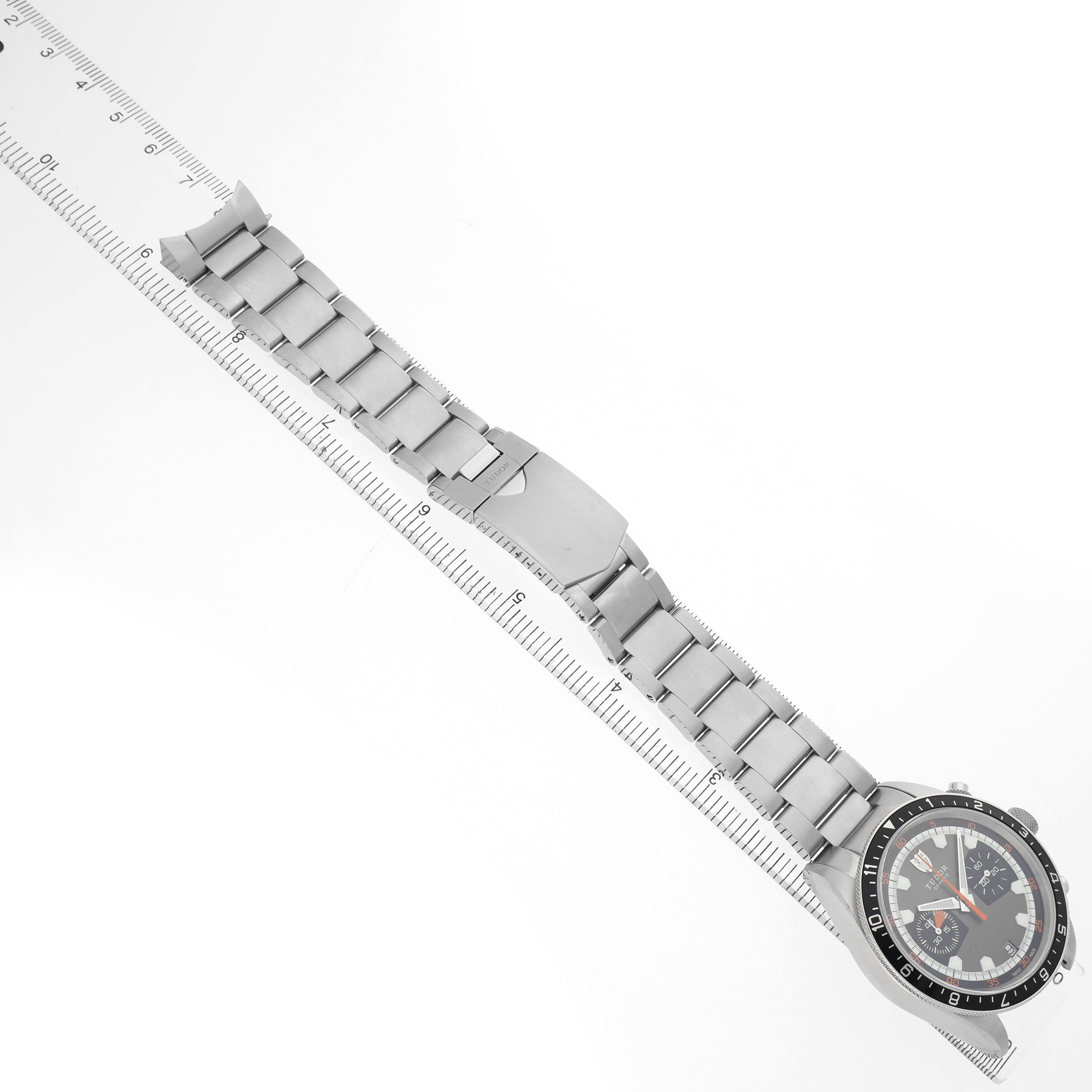 The Tudor Heritage Chrono 70330N-65740 Men's Stainless Steel Grey Dial watch is shown from an overhead angle, featuring the face, bezel, and full metal bracelet.