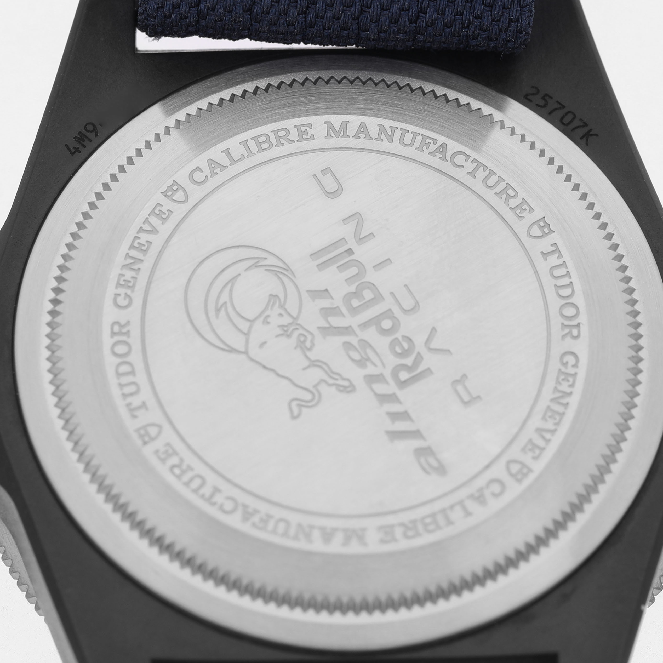 The image shows the back case of a Tudor Pelagos 25707KN Men's Titanium Blue Dial watch, highlighting engravings and the strap attachment.