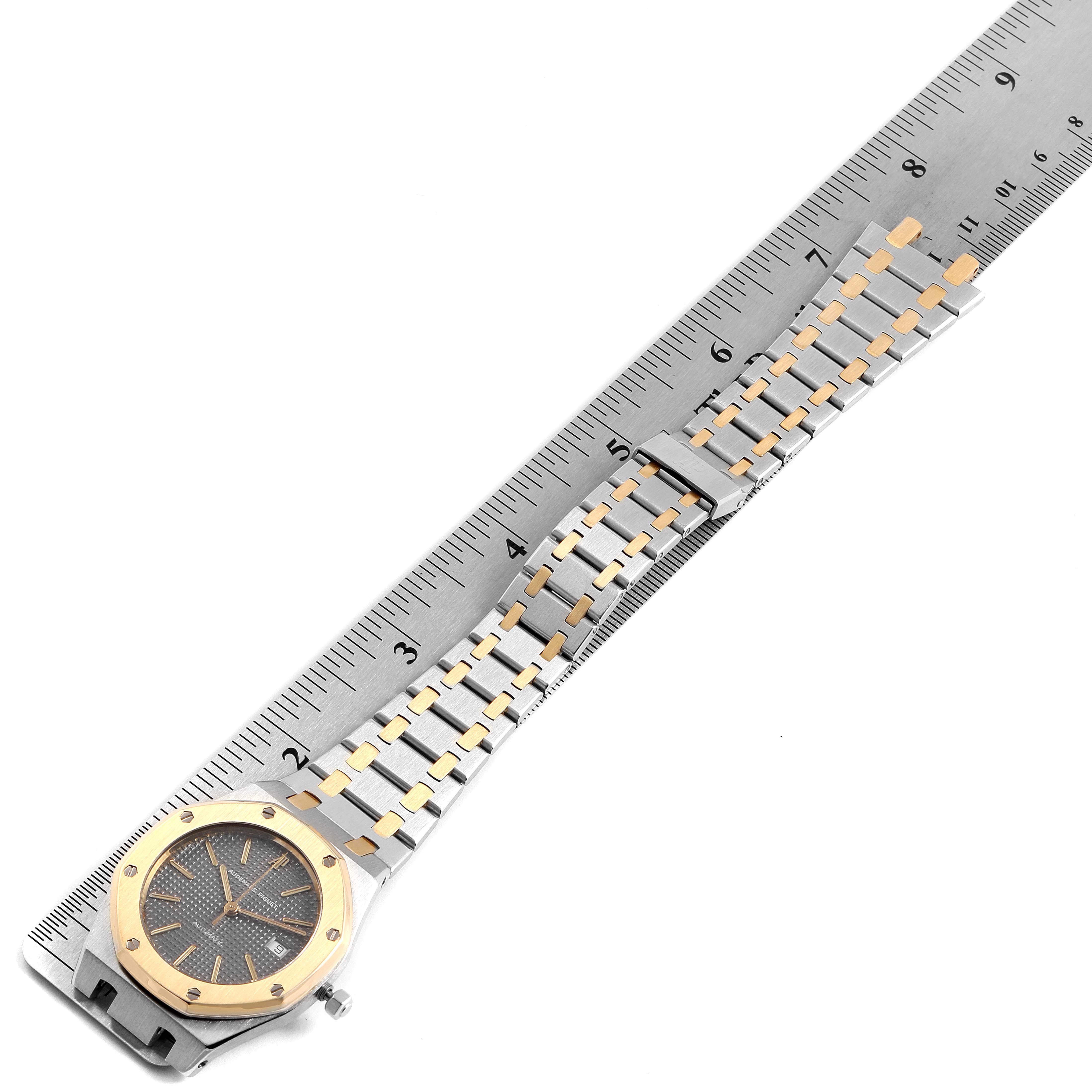 The image shows a top-down view of an Audemars Piguet Royal Oak SA14486 Men's Steel and Gold (two tone) Grey Dial SA14486 Men's Steel and Gold (two tone) Grey Dial watch, focusing on the face and full bracelet, with a ruler for scale.