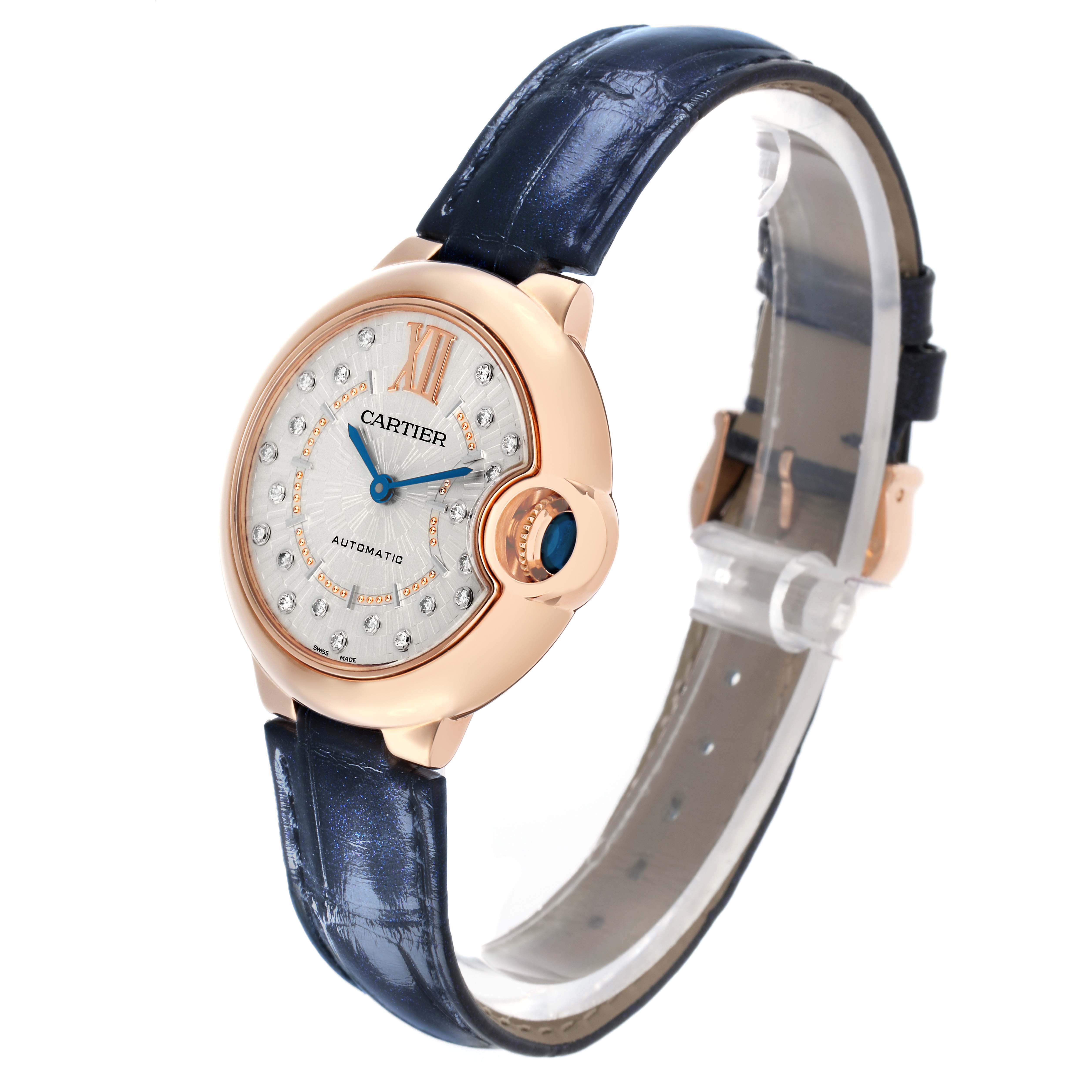 The Cartier Ballon Bleu WGBB0052 Women's Rose Gold Silver Dial watch is shown at a three-quarter angle, highlighting its round face, crown, and blue leather strap.