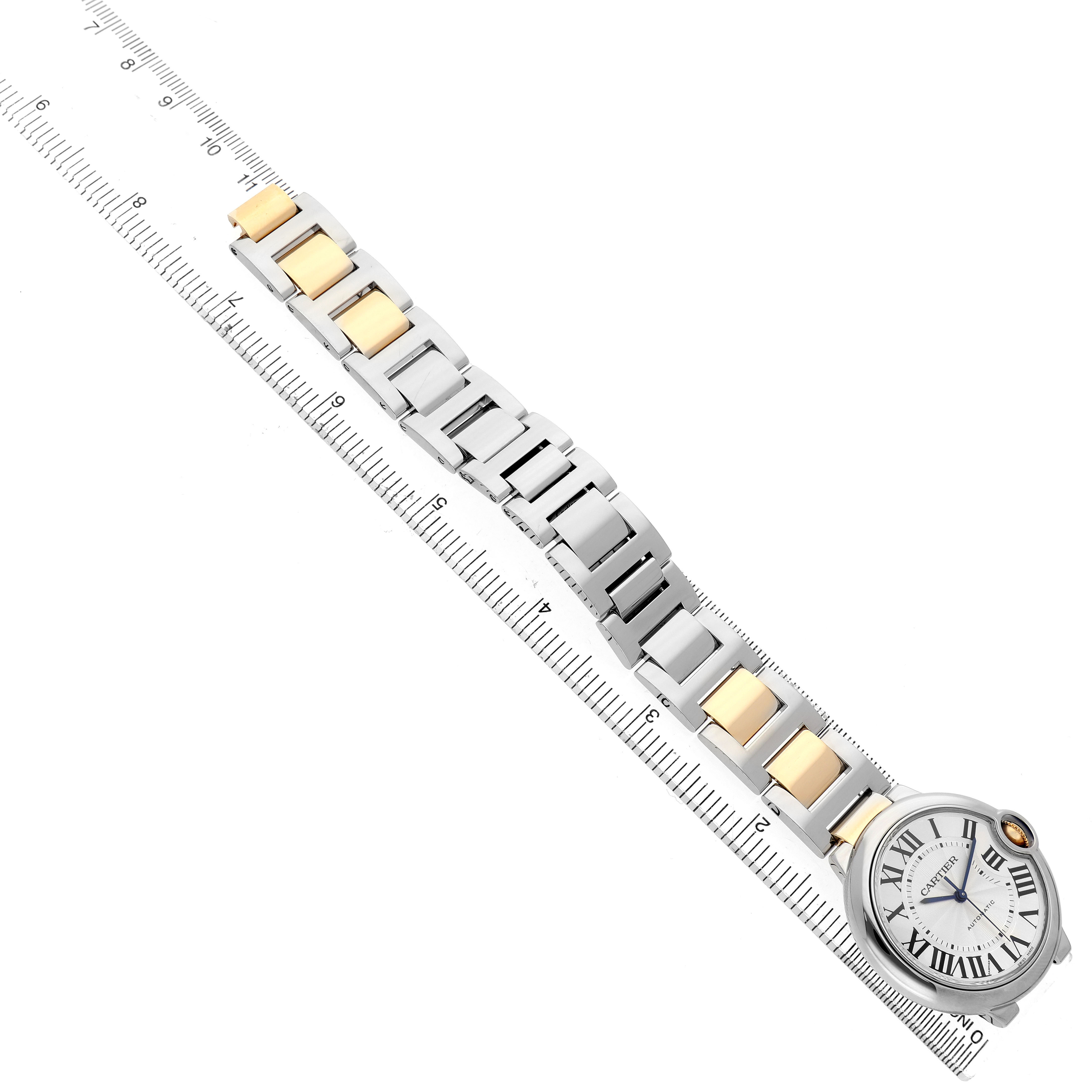 The image shows a Cartier Ballon Bleu W6920047 Women's Stainless Steel Silver Dial watch laid flat with its face and metal bracelet visible, aligned beside a ruler.