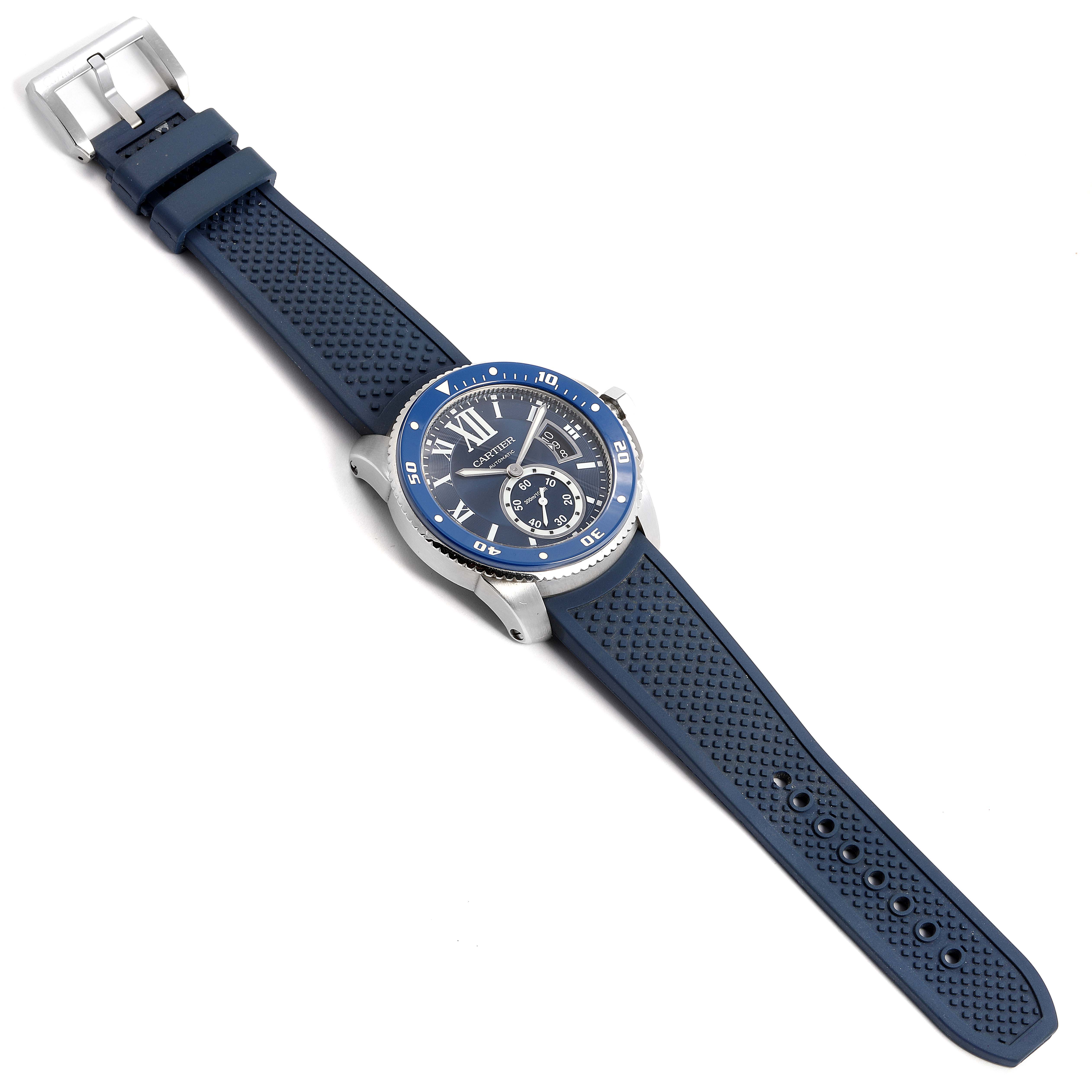 The Calibre de Cartier watch is shown at an angled view, highlighting its blue bezel, dial, and rubber strap.
