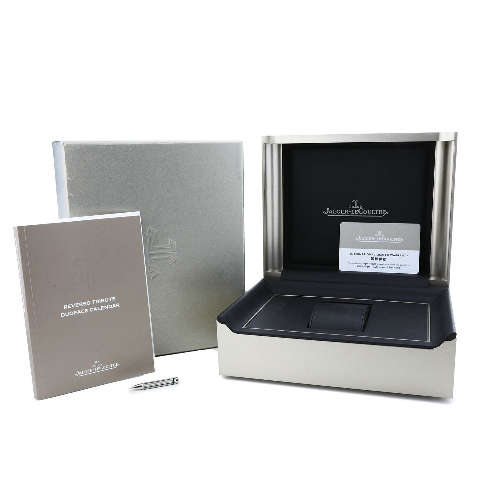 The image shows the packaging for the Jaeger-LeCoultre Reverso model, including the box, manual, pen, and warranty card.