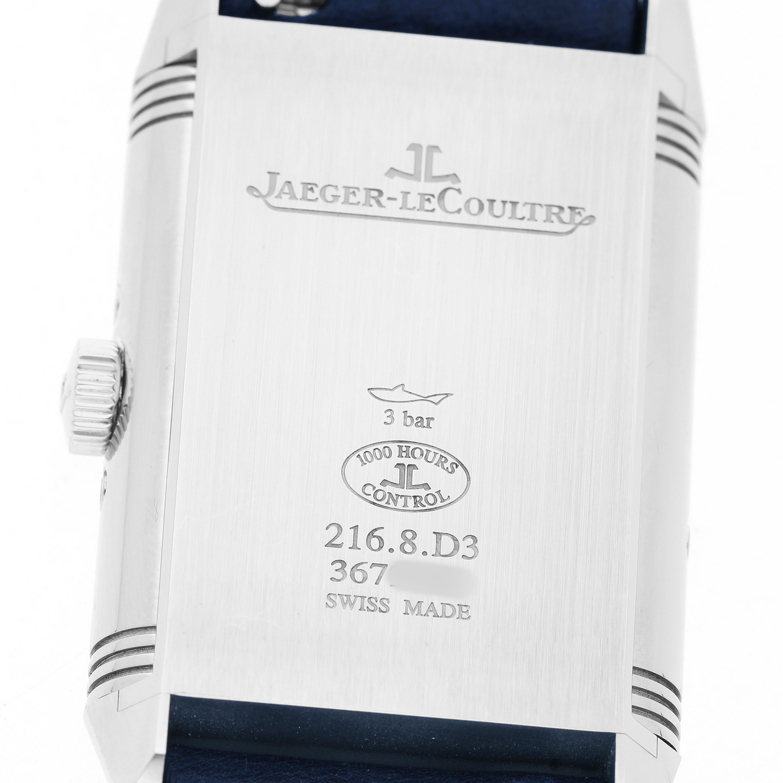 The image shows the back of a Jaeger-LeCoultre Reverso watch, featuring engravings and the crown on the side.