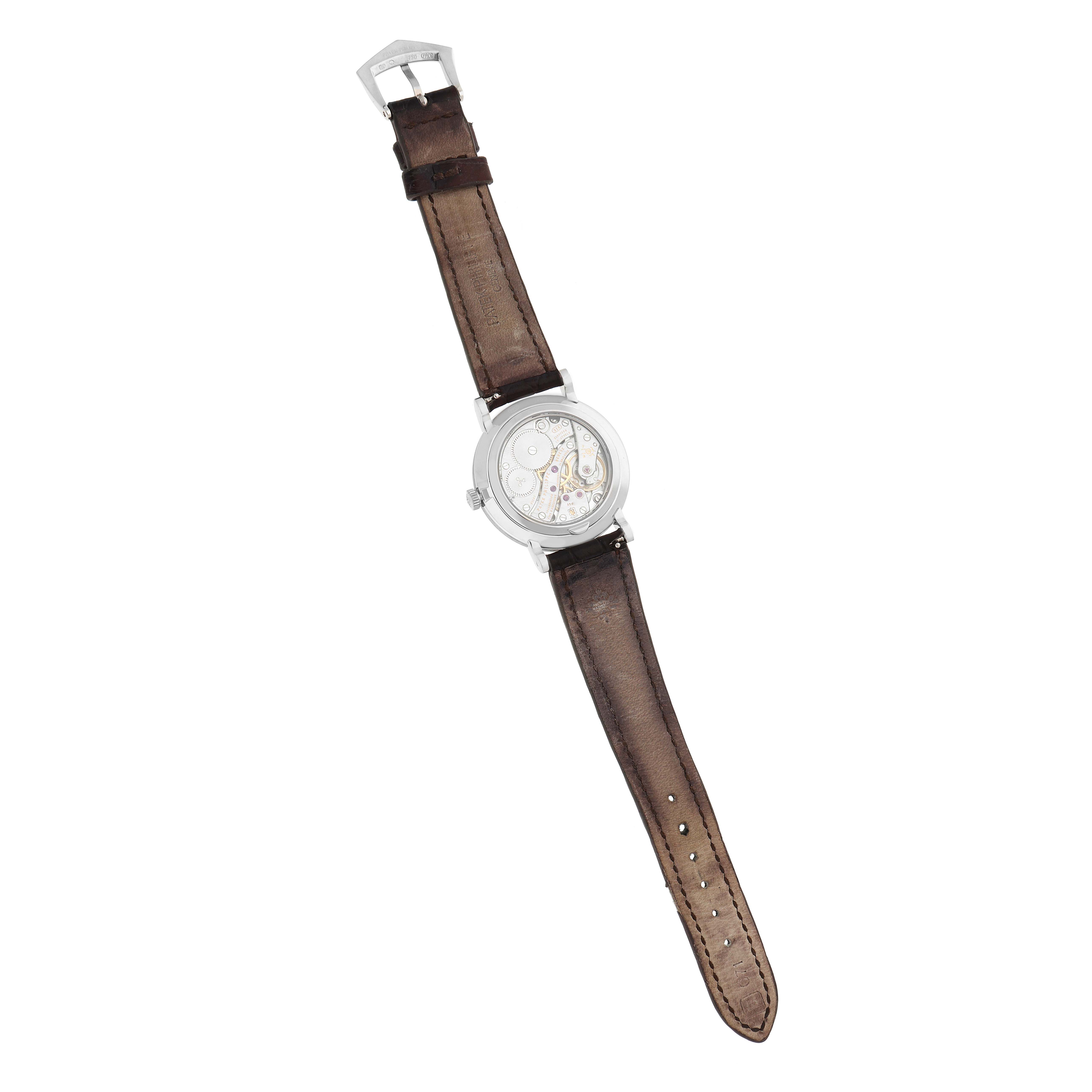 The Patek Philippe Calatrava 7119G Women
s White Gold White Dial watch is shown from above, displaying its leather strap and case back revealing the movement.