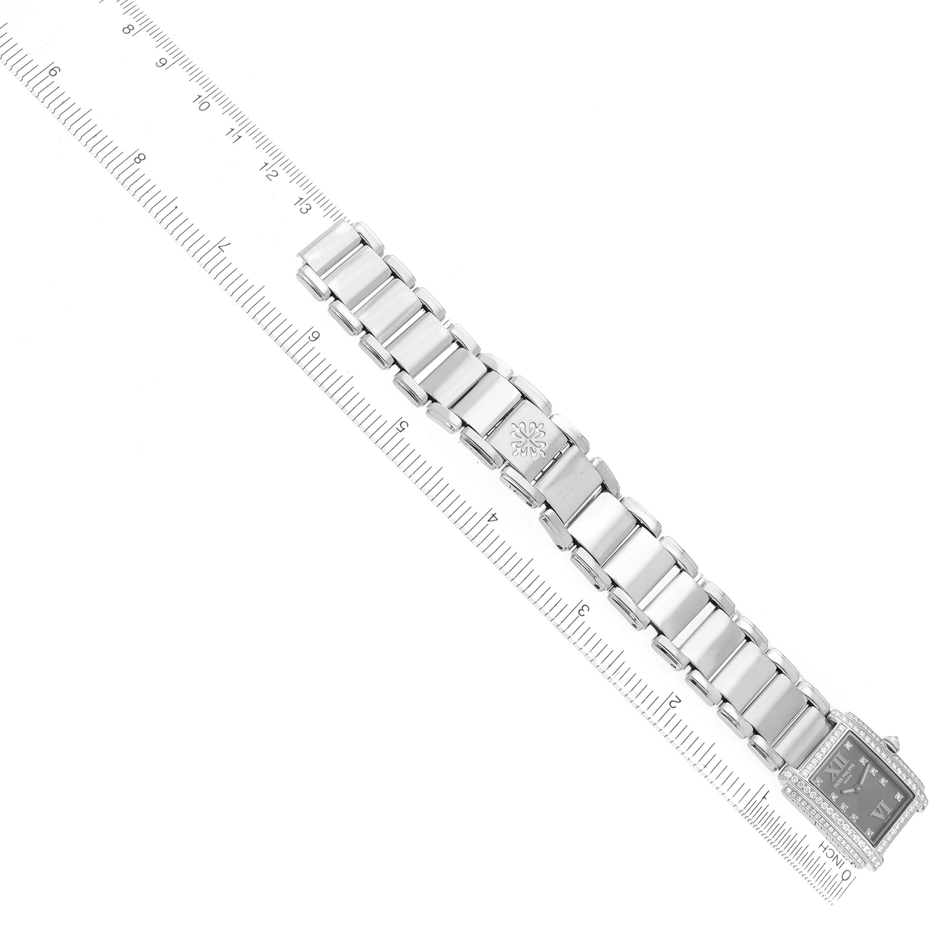 The image shows a top-down view of a Patek Philippe Twenty-4 4908G Women
s White Gold Silver Dial watch with its bracelet and rectangular dial alongside a ruler.
