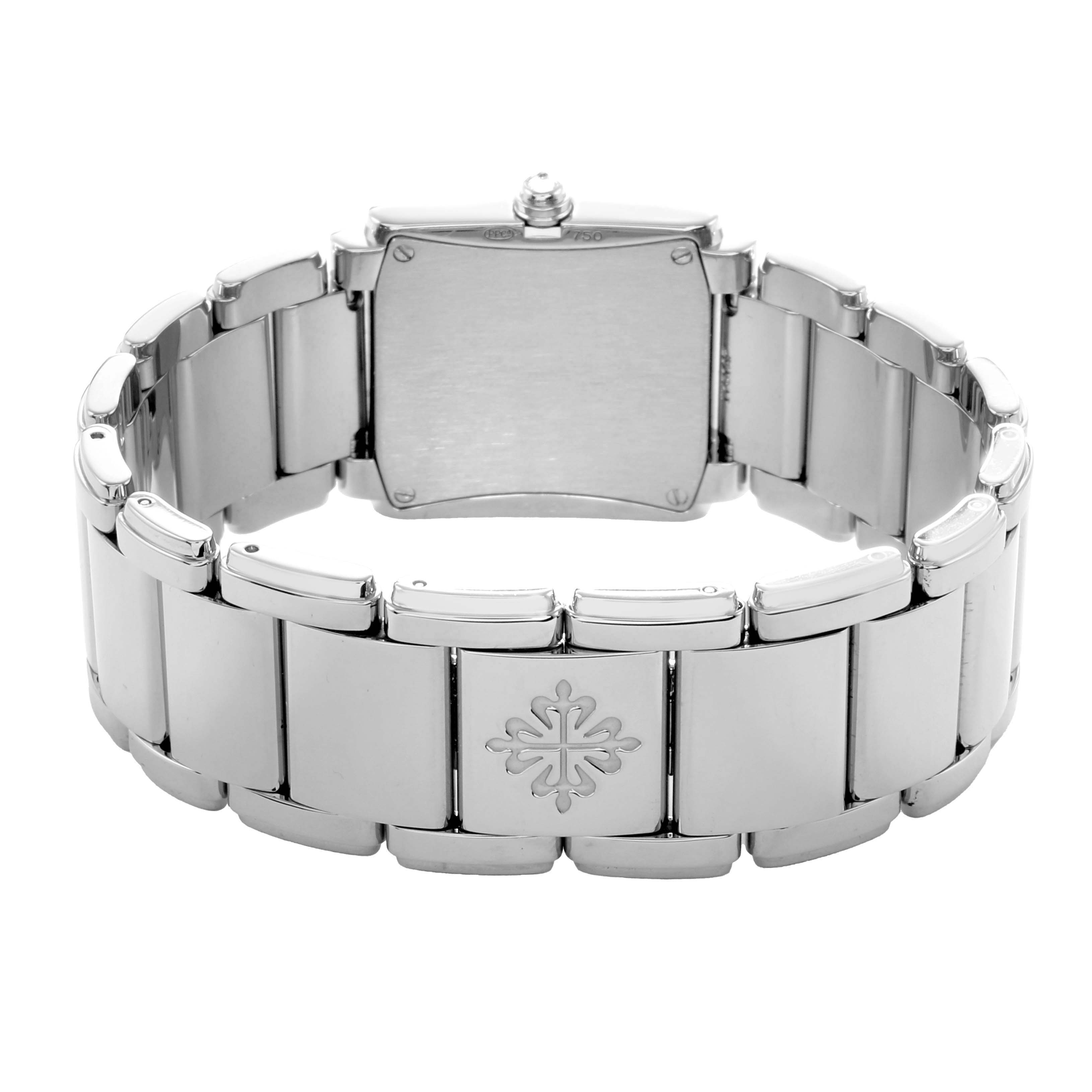 The Patek Philippe Twenty-4 4910/20G-001 Women's White Gold Silver Dial watch is shown from the back, highlighting the bracelet and clasp with the brand logo.