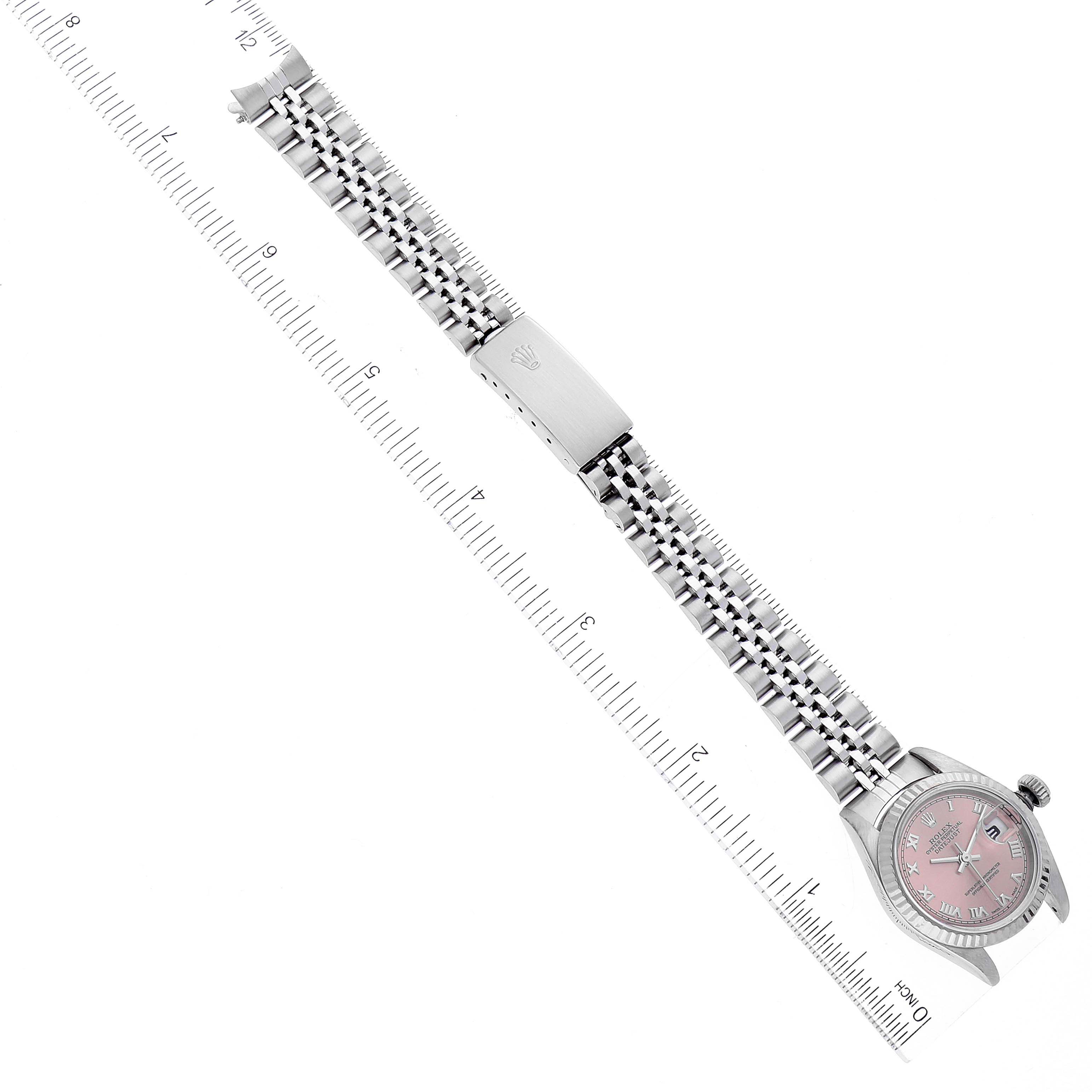 This image shows a top-down view of a Rolex Datejust 79174 Women's Stainless Steel Pink Dial 79174 Women's Stainless Steel Pink Dial watch, displaying its bracelet, clasp, and pink dial next to a ruler.